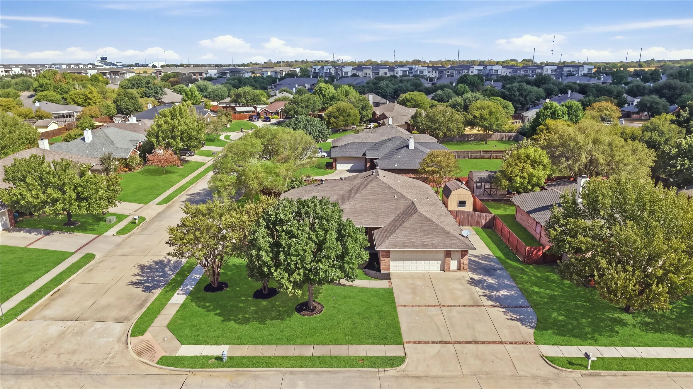Brick exterior with a gabled roof, attached two-car garage, concrete driveway, and established landscaping