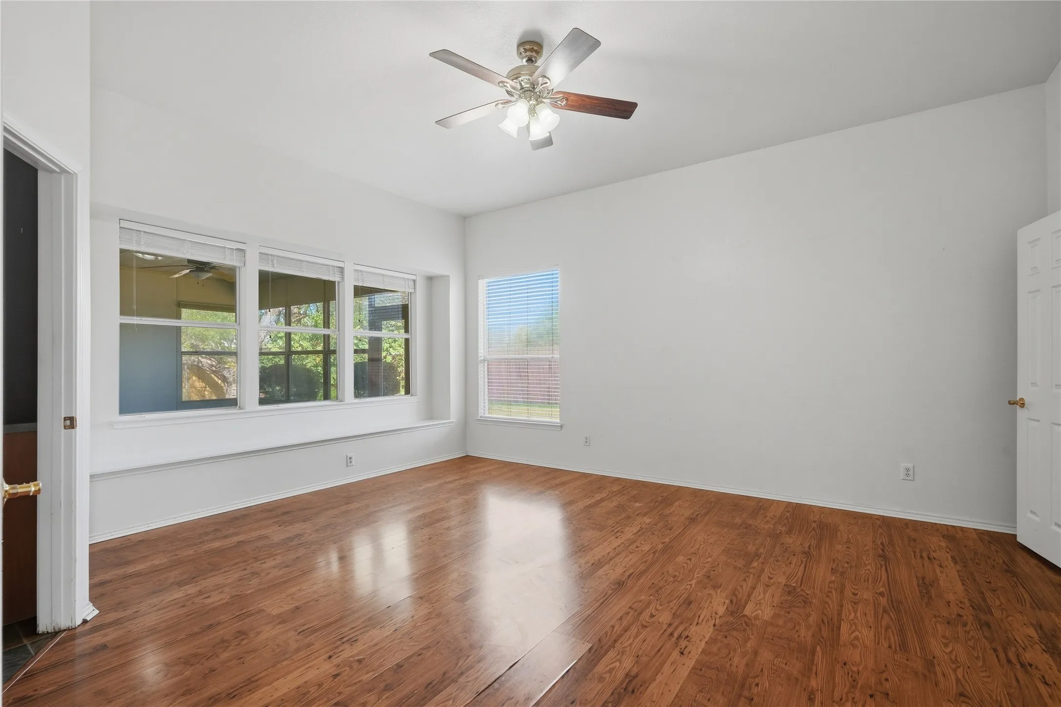 Wood-finish flooring throughout, vaulted ceiling, and a ceiling fan with light fixture