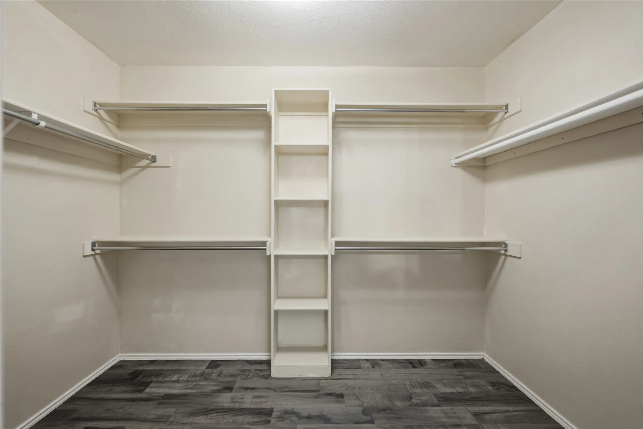 Built-in shelving, multiple hanging rods, and wood-finish flooring
