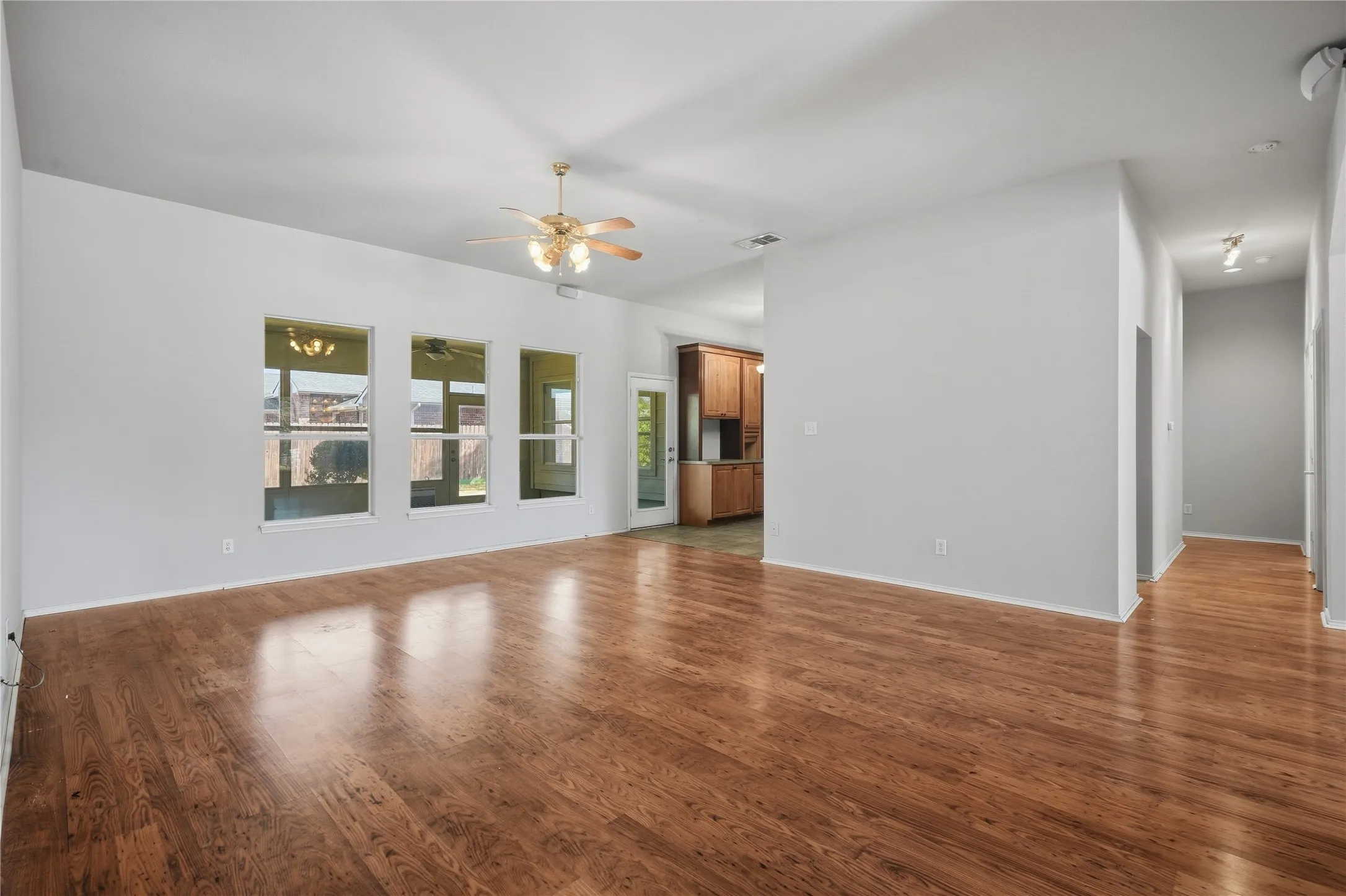 Spacious interior with wood-finish flooring, multiple windows, vaulted ceiling, and a ceiling fan