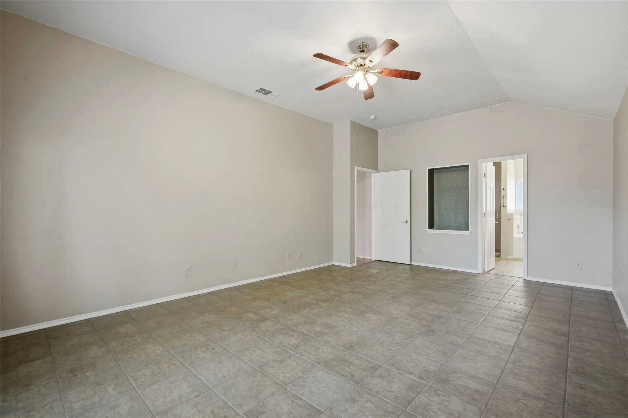 Vaulted ceiling, ceiling fan, neutral wall tones, tile flooring, interior doors