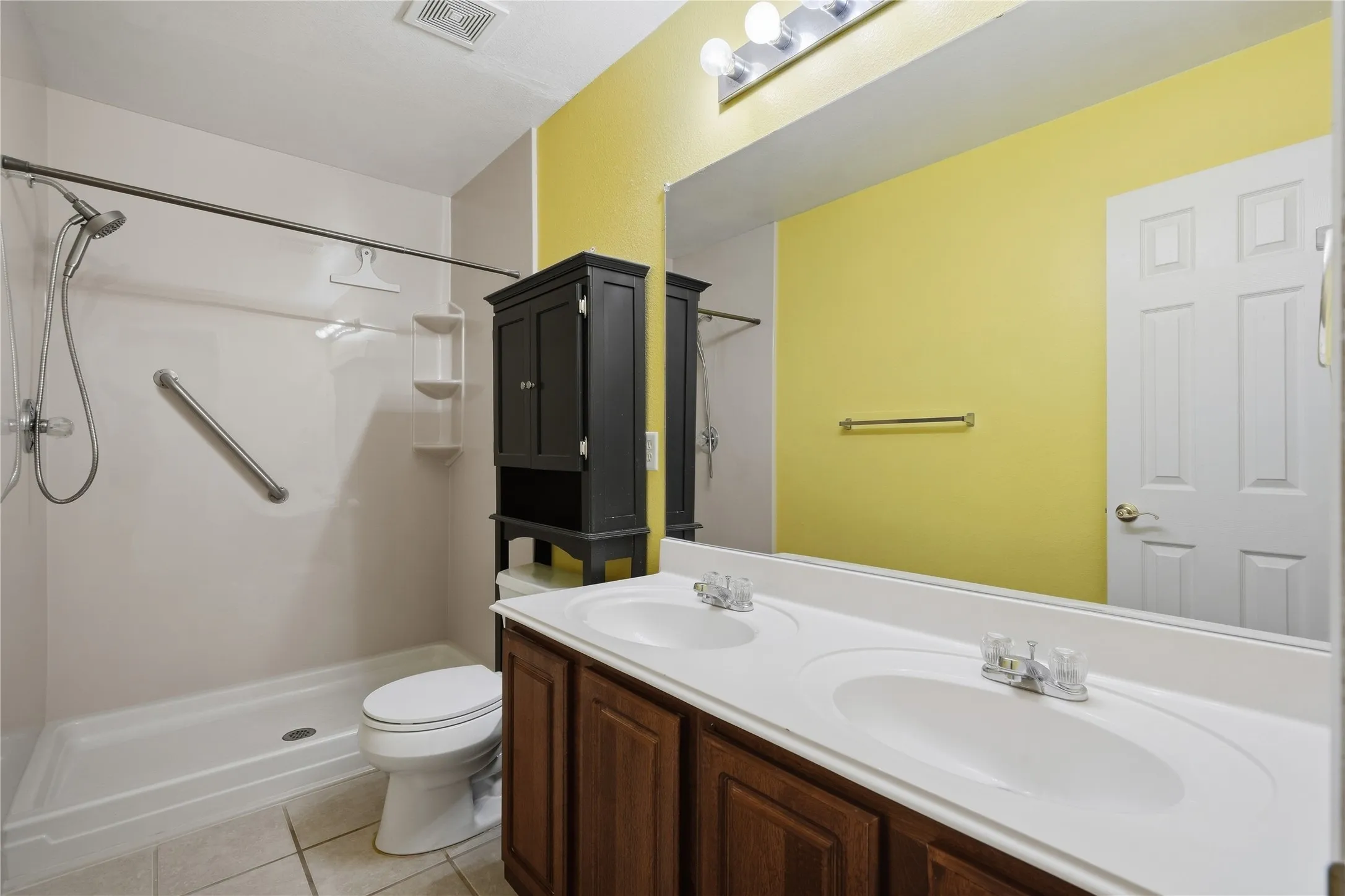 Dual vanity with integrated sinks, wood-finish cabinetry, and a wide mirror