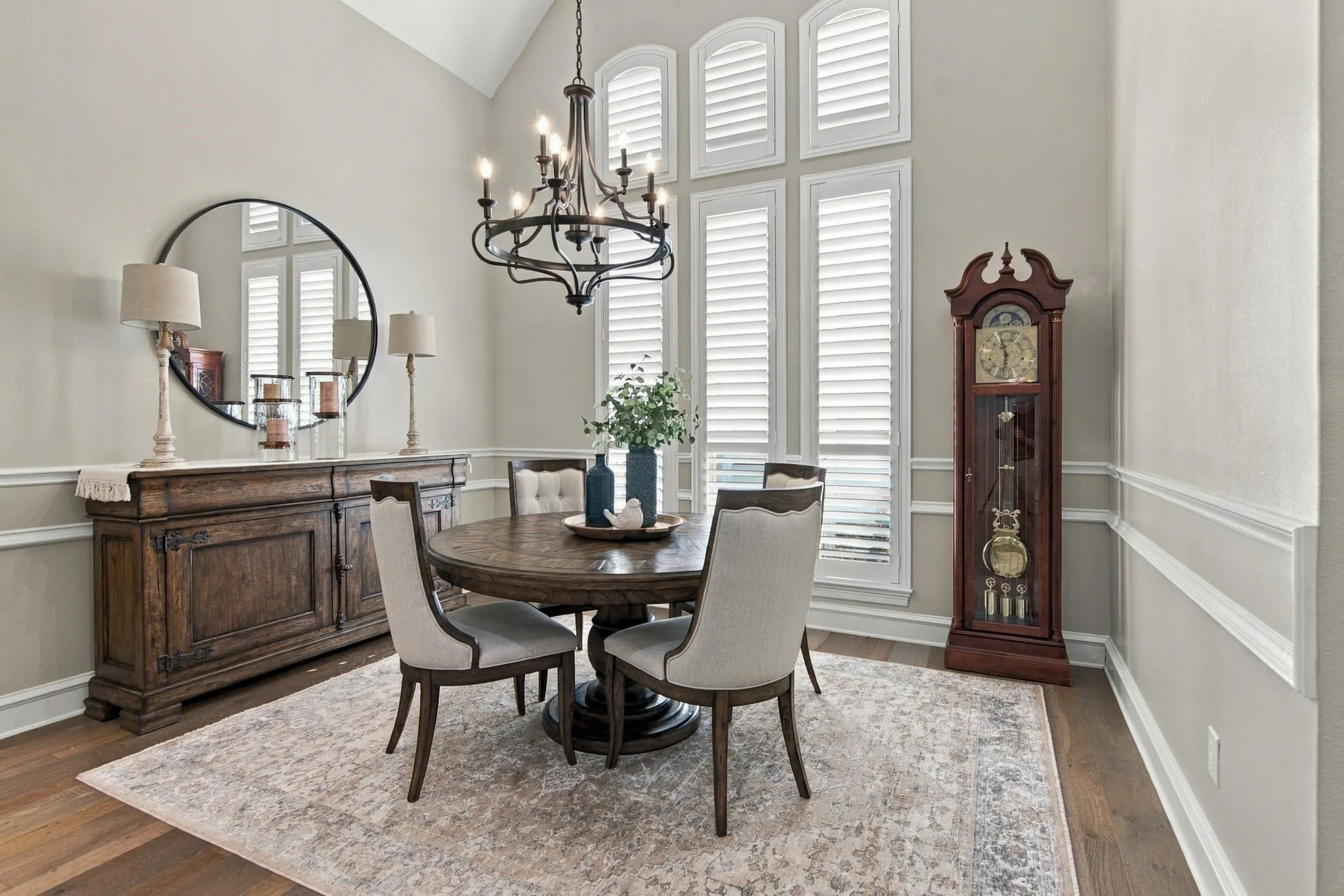The beautiful dining room is perfect for entertaining, features high ceilings, a decorative chandelier, plantation shutters, wood flooring, and extensive crown molding.