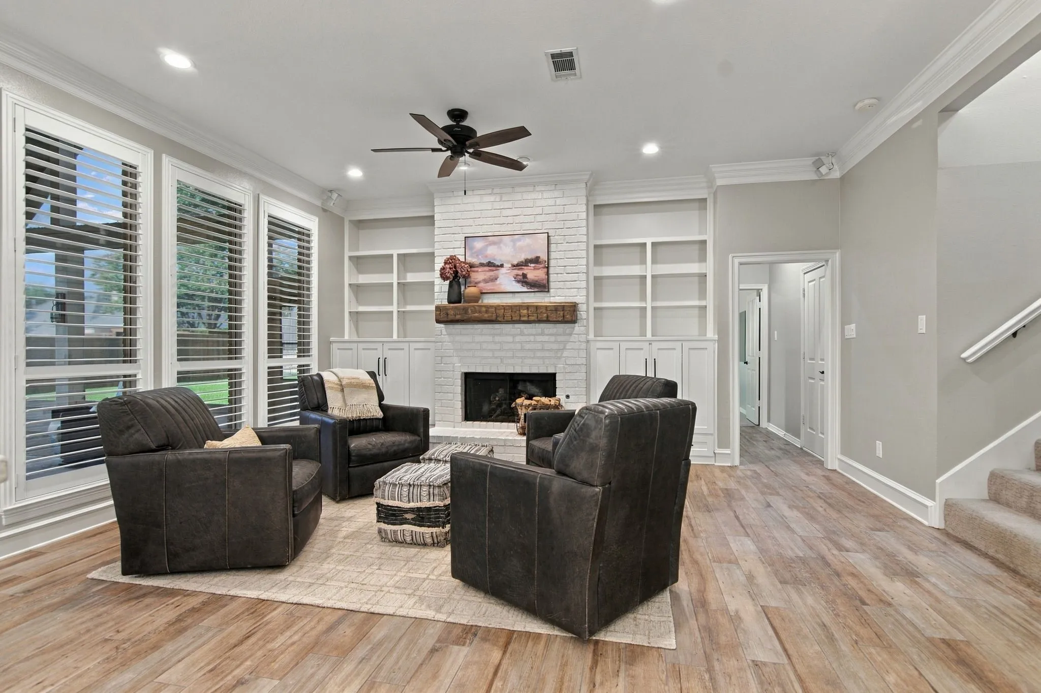 Wood-finish flooring throughout, the family room features a ceiling fan, and recessed lighting.  A custom hand-hewn mantle highlights the wood burning fireplace.  Hallway leads to the first floor guest bedroom and bath.