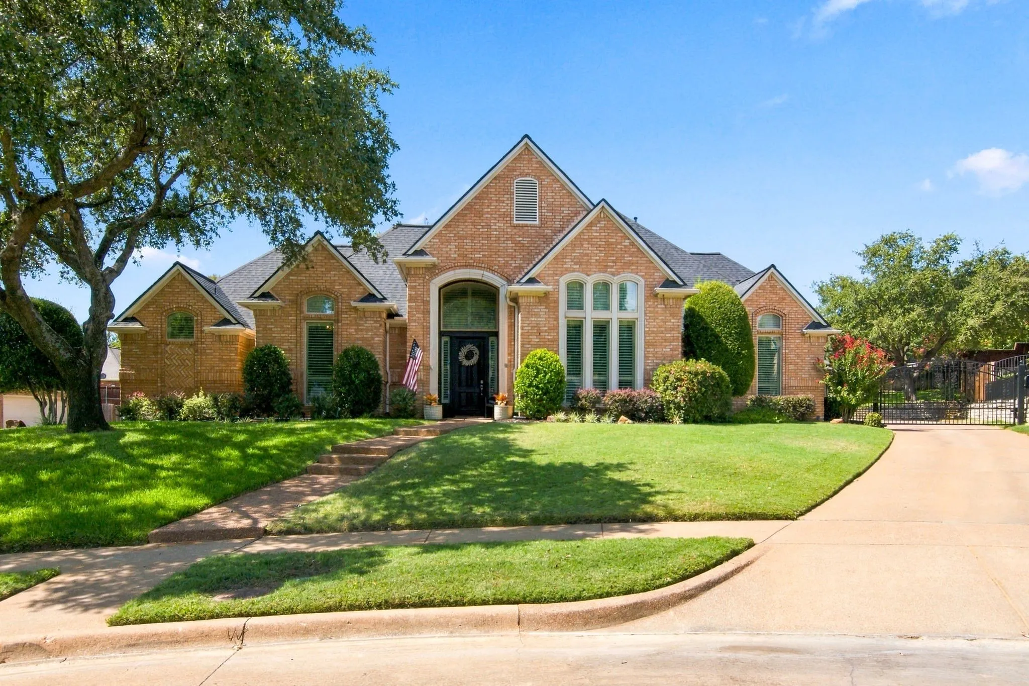 Welcome Home!  Beautiful brick exterior with an arched capstone entry, formal windows, mature landscaping, and electric gate.