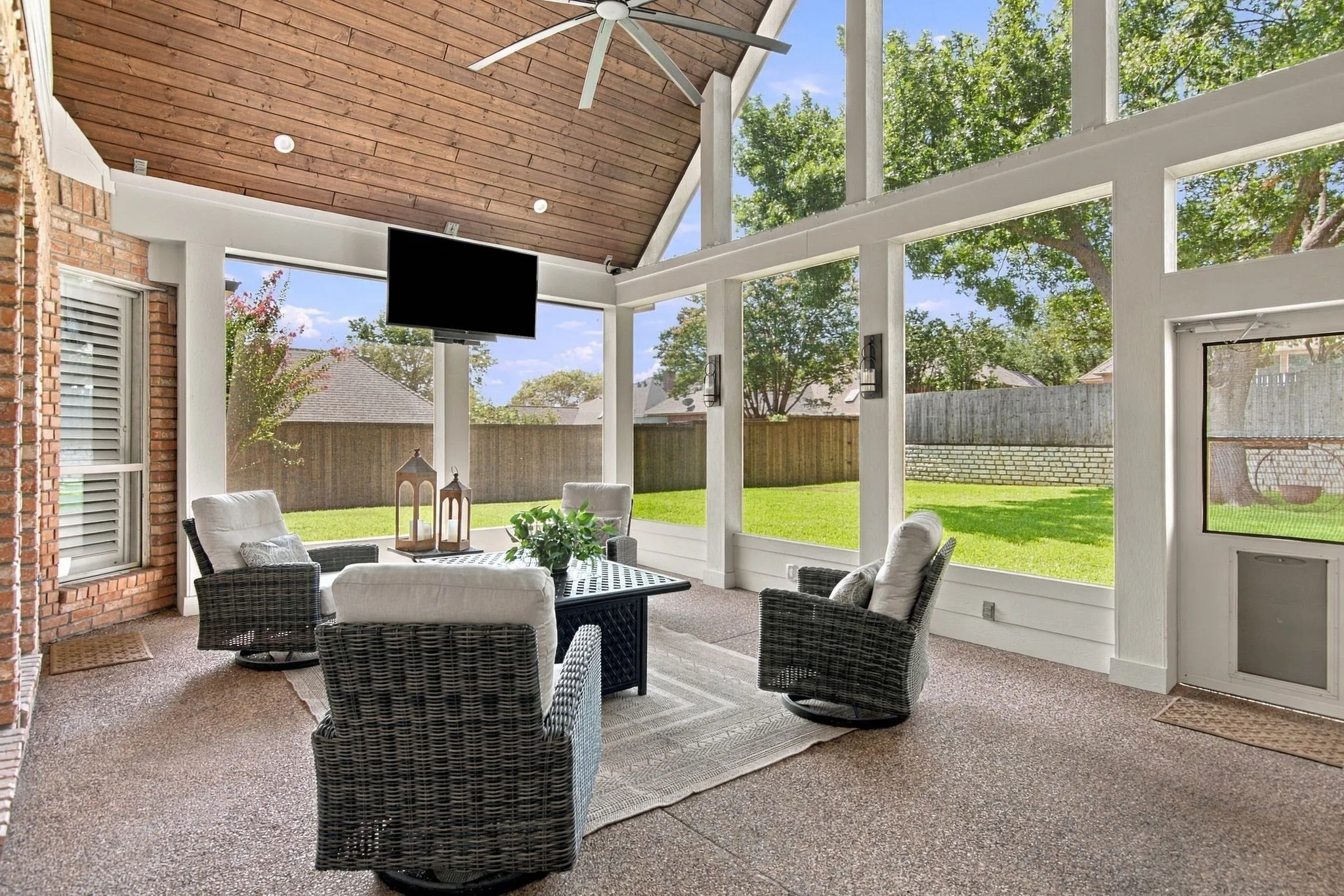 Screened outdoor space extends your living space for morning coffee or entertaining!  Features vaulted wood-paneled ceiling, ceiling fan, and exposed brick wall.  The flat-screen TV is hung on an electric mount to drop down for perfect viewing.