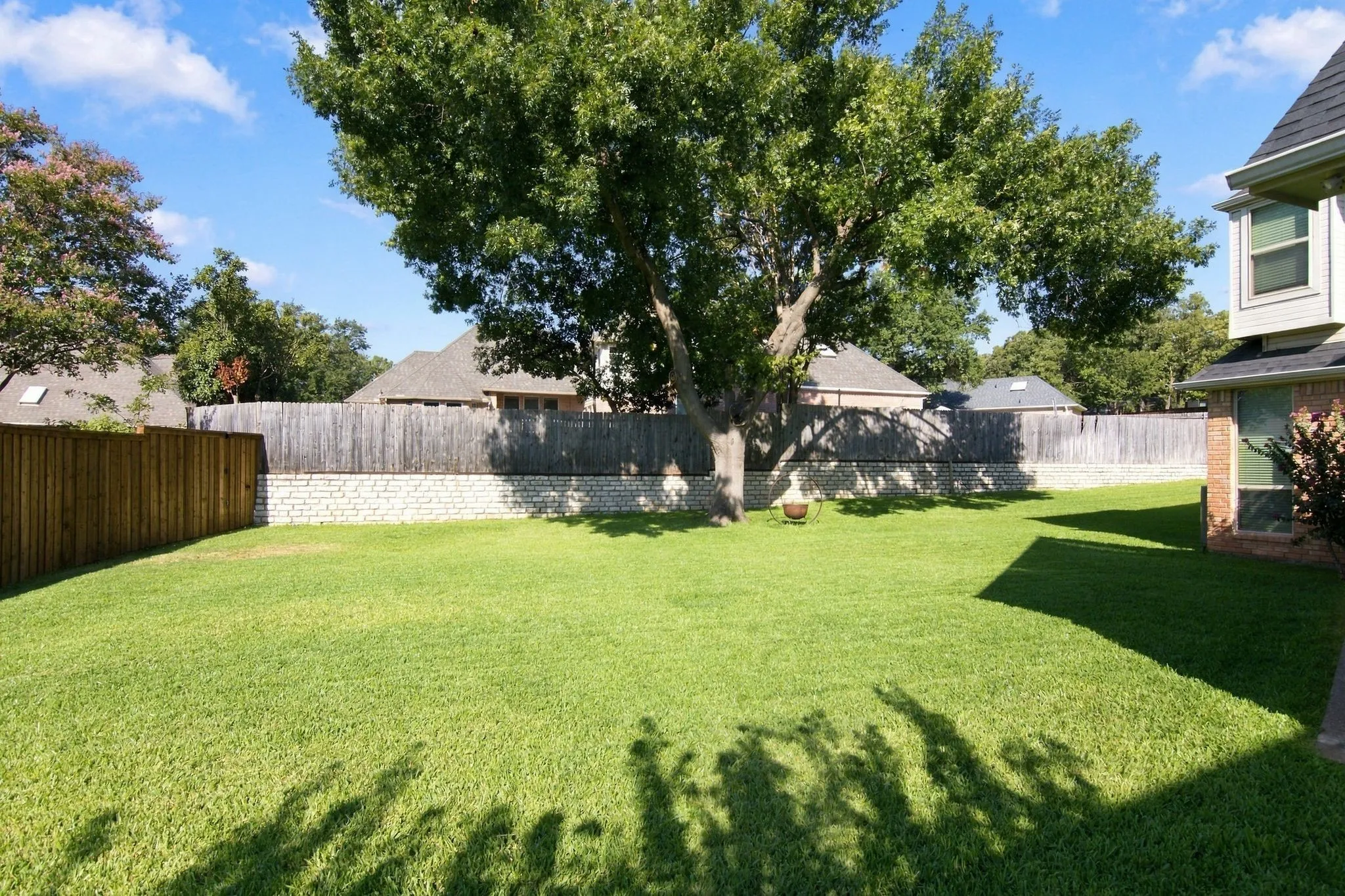 Expansive beautiful lawn is perfect for all family activities or creating your outdoor oasis.  Mature tree, bordered by a wood privacy fence and stone retaining wall.