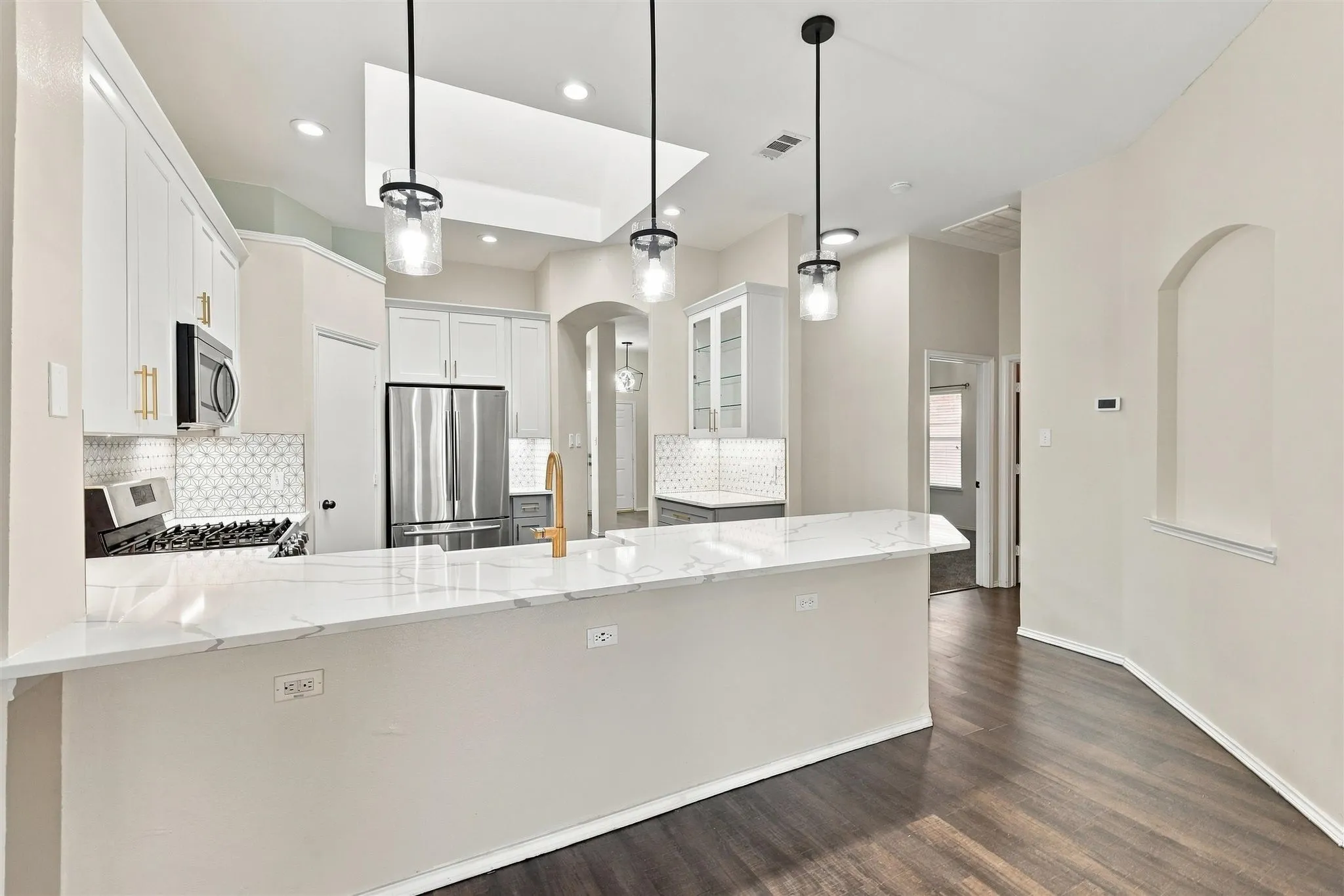 Kitchen featuring white cabinetry, stainless steel appliances, a marble-look countertop, wood-finish flooring, and recessed lighting
