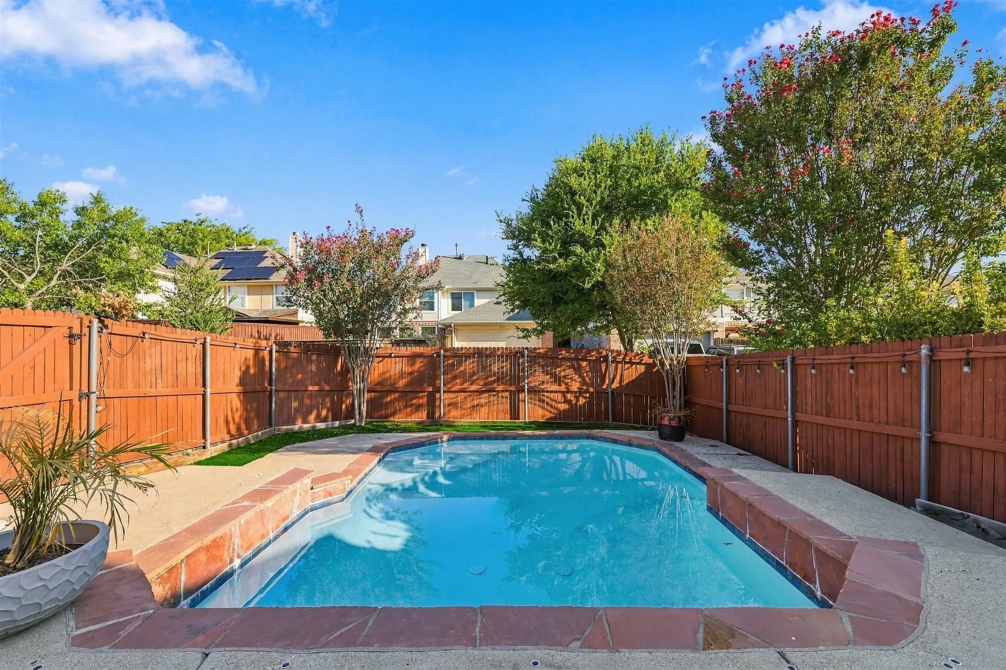 In-ground swimming pool with flagstone coping, surrounding concrete patio, and privacy fencing
