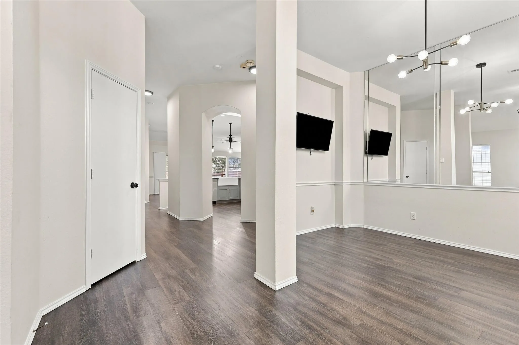 Wood-finish flooring throughout, a modern chandelier, and arched doorways enhance the interior