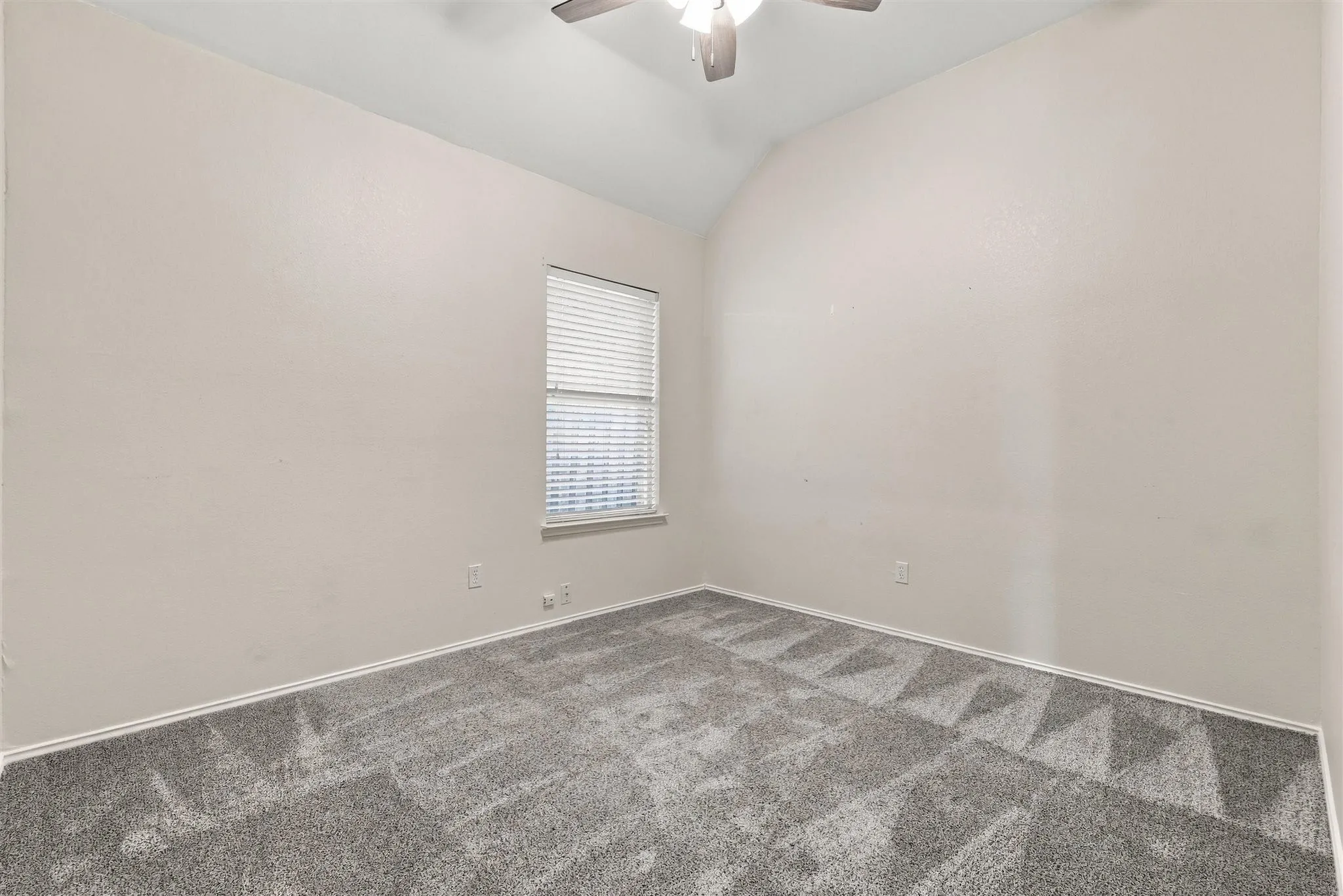 Vaulted ceiling, ceiling fan, neutral wall tones, window with blinds, and patterned carpeting