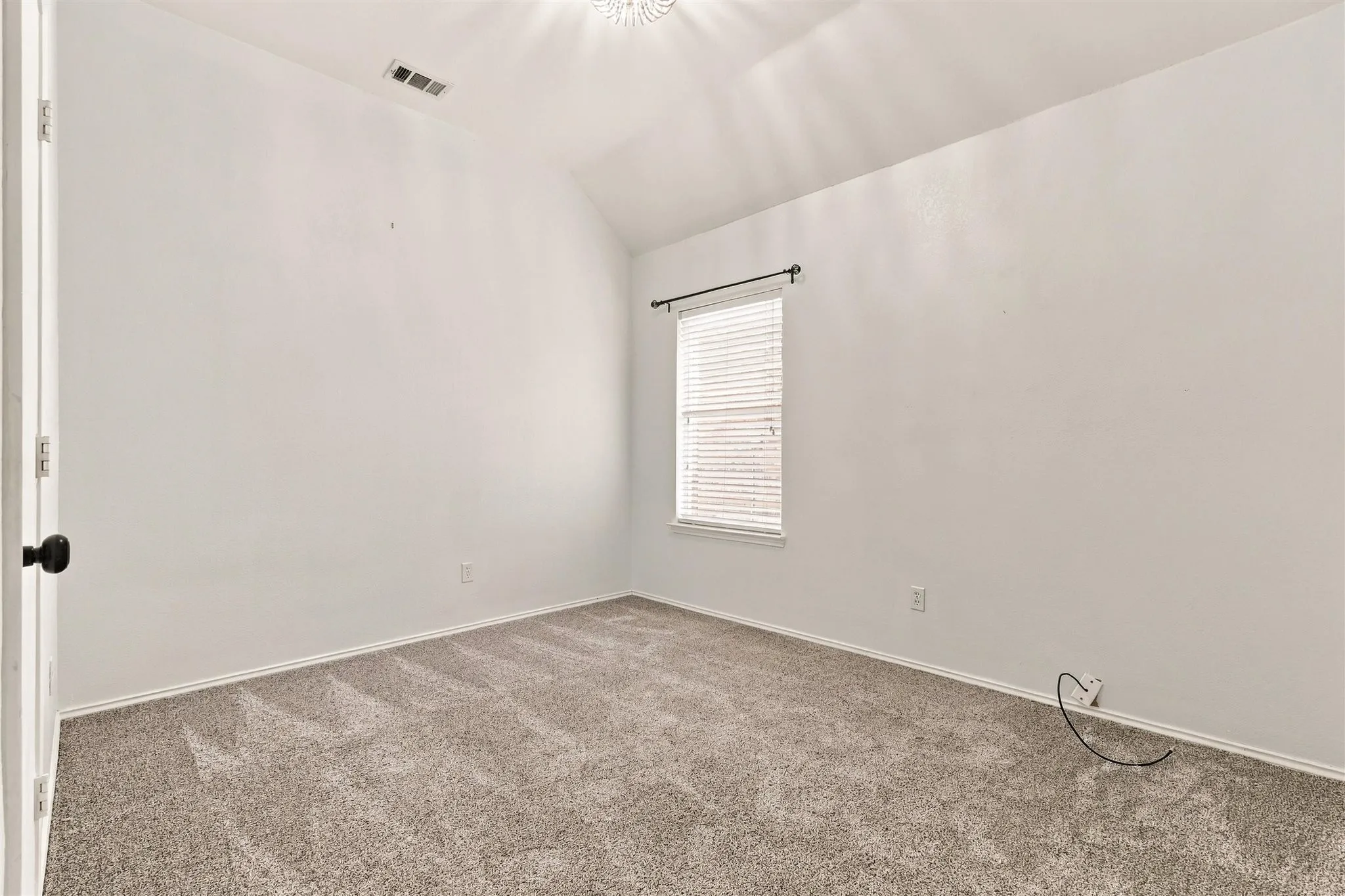 Vaulted ceiling with an attached light fixture, window with blinds, and neutral carpeting
