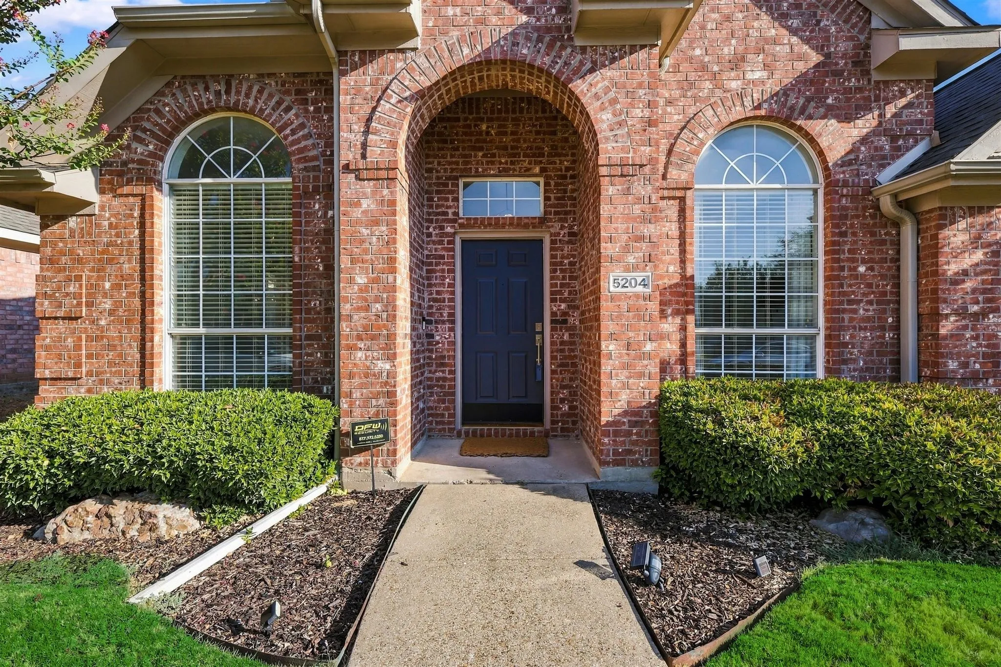 Brick facade with an arched entry, dark front door, and arched transom window
