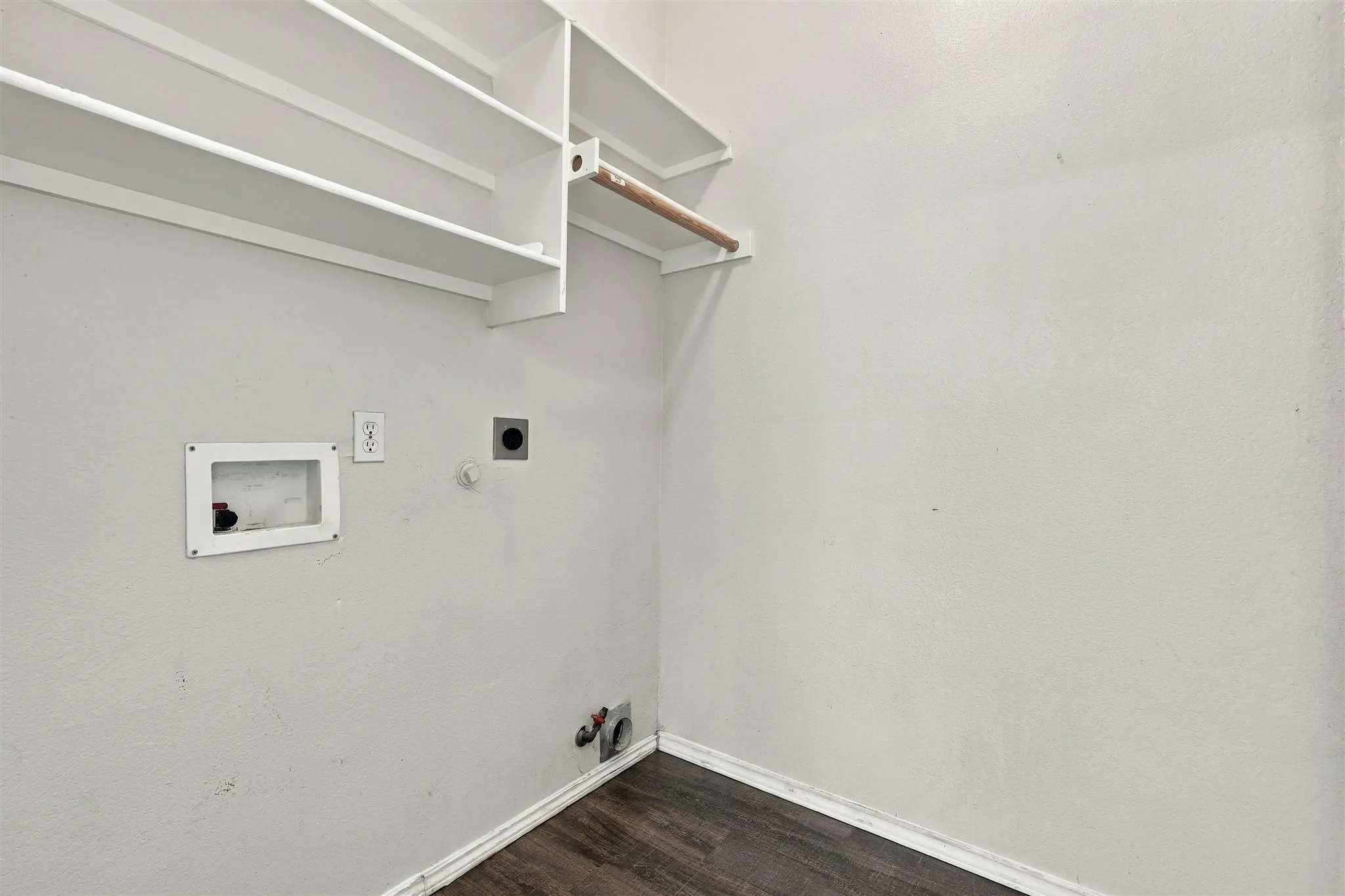 Laundry room with built-in shelving, a clothes hanging rod, and wood-finish flooring