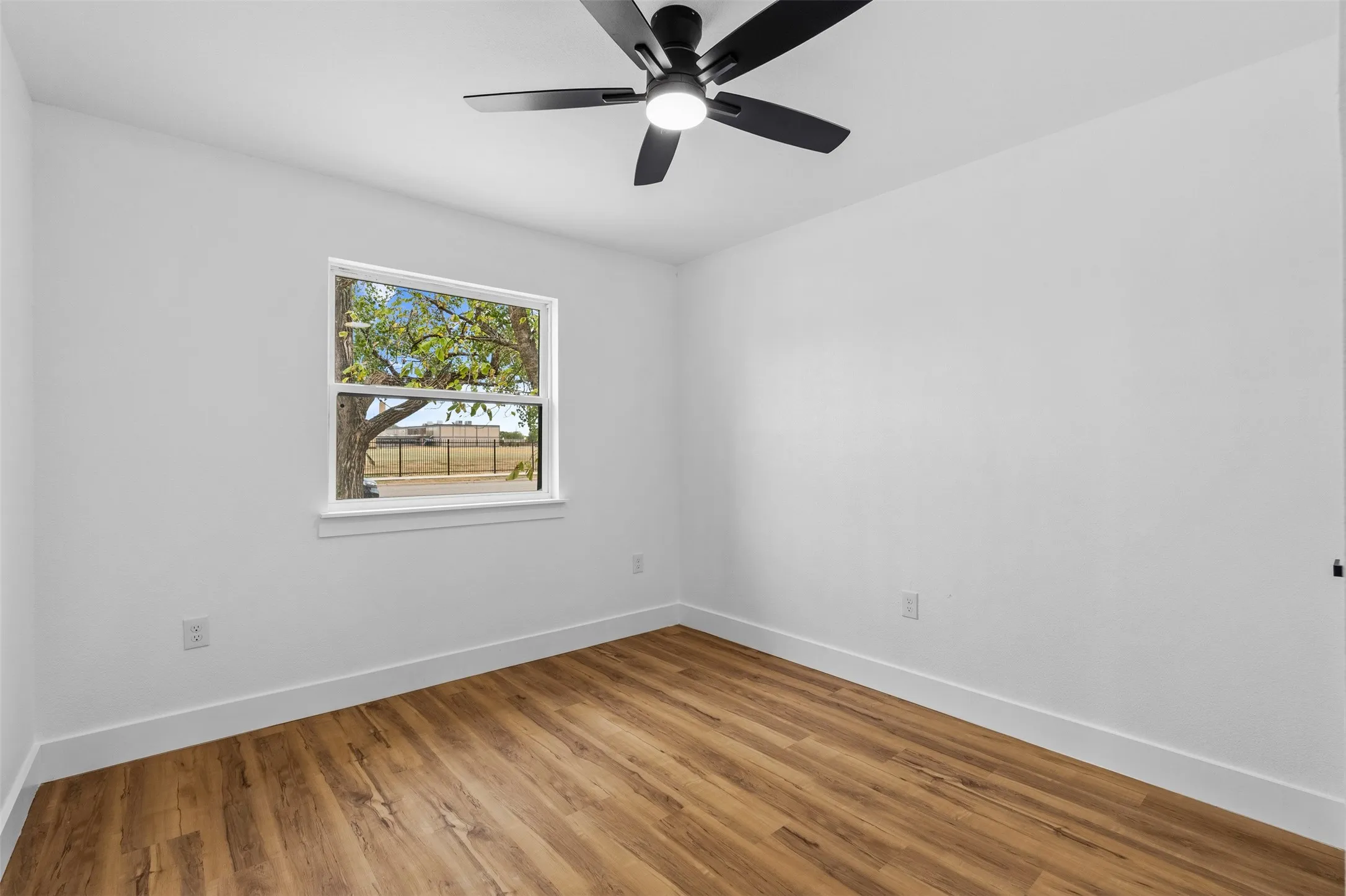 Wood-finish flooring, white walls, and a modern ceiling fan with integrated lighting