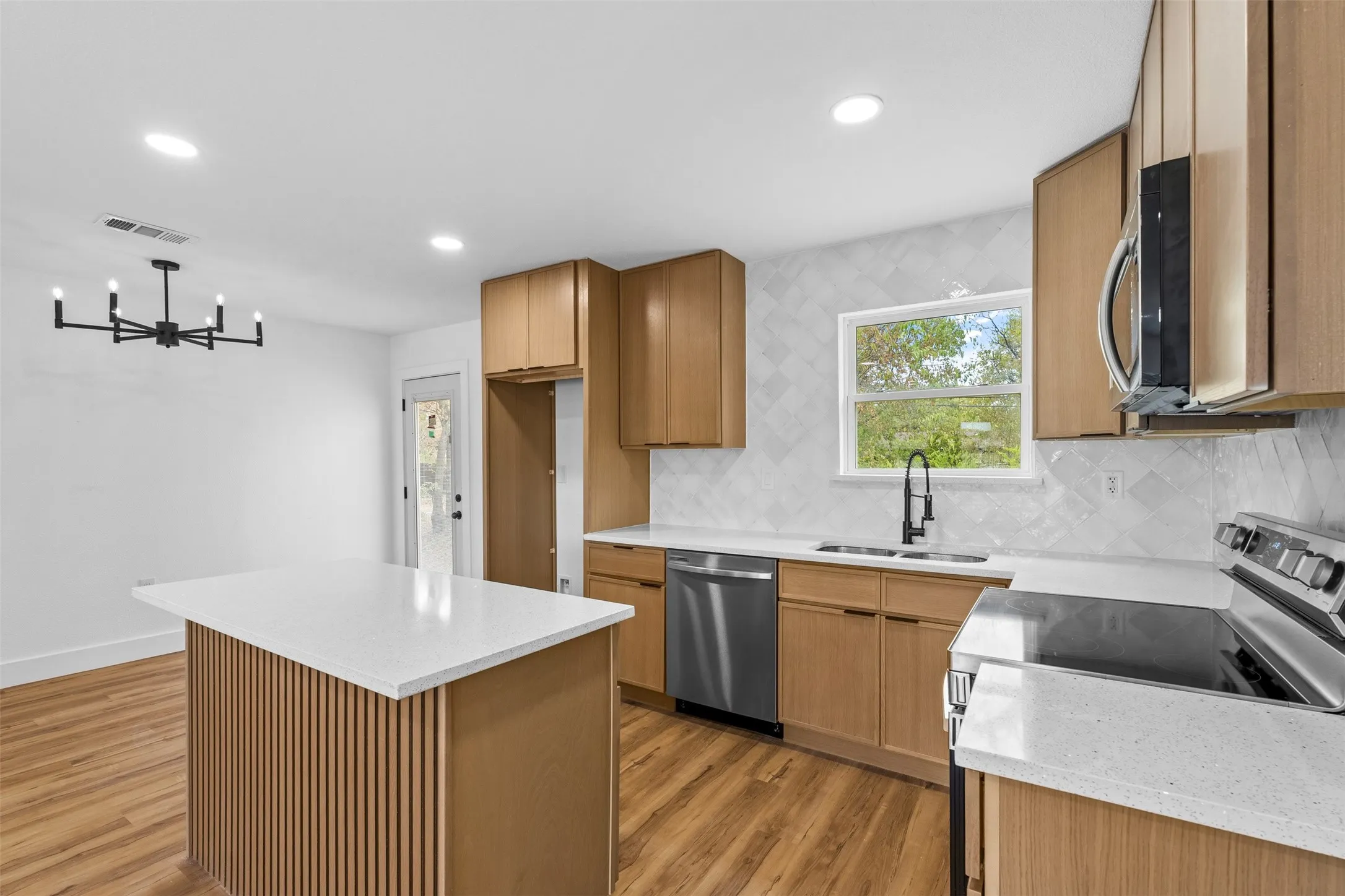 Kitchen featuring wood-finish cabinetry, white countertops, stainless steel appliances, and a tiled backsplash