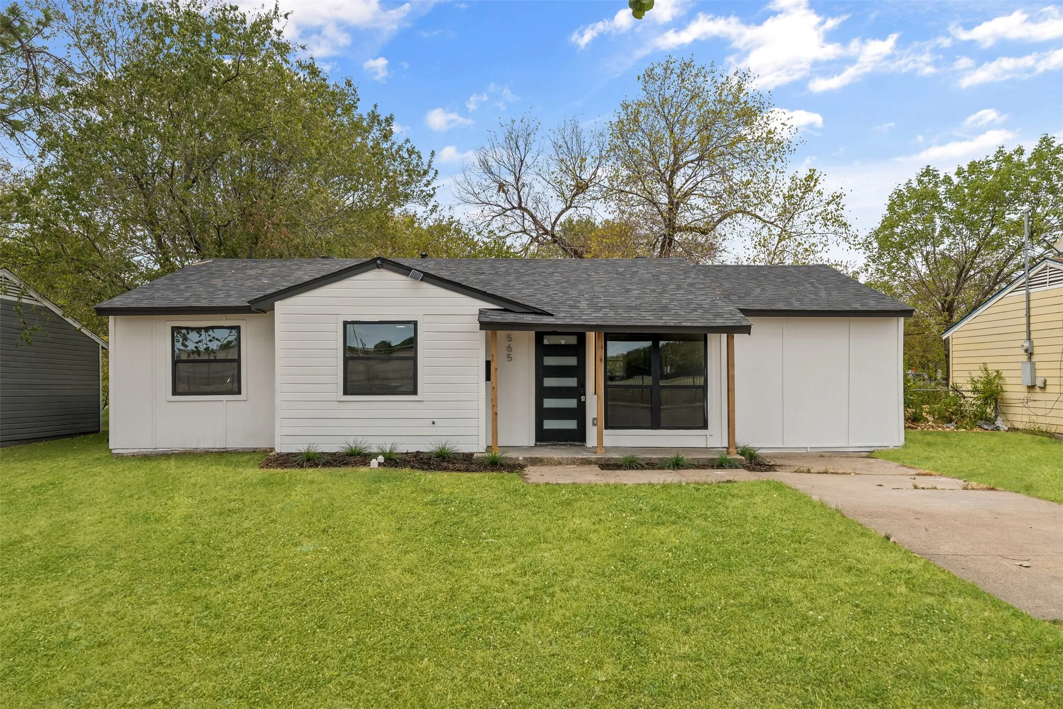 Modern exterior with white siding, black trim windows, a dark shingle roof, and a contemporary front door with vertical glass panels
