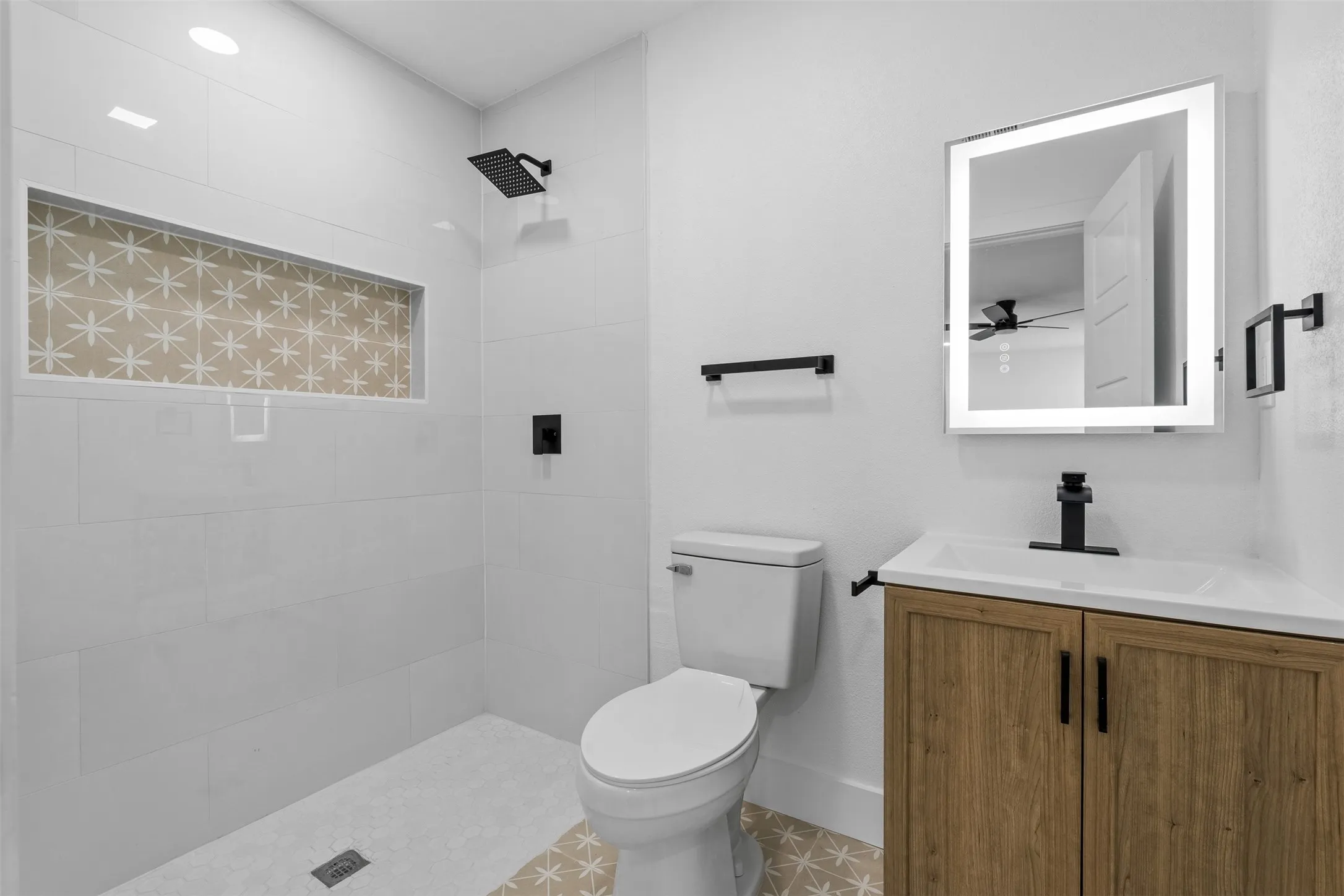 Walk-in shower with a decorative tiled niche, black shower fixtures, and white subway tile surround