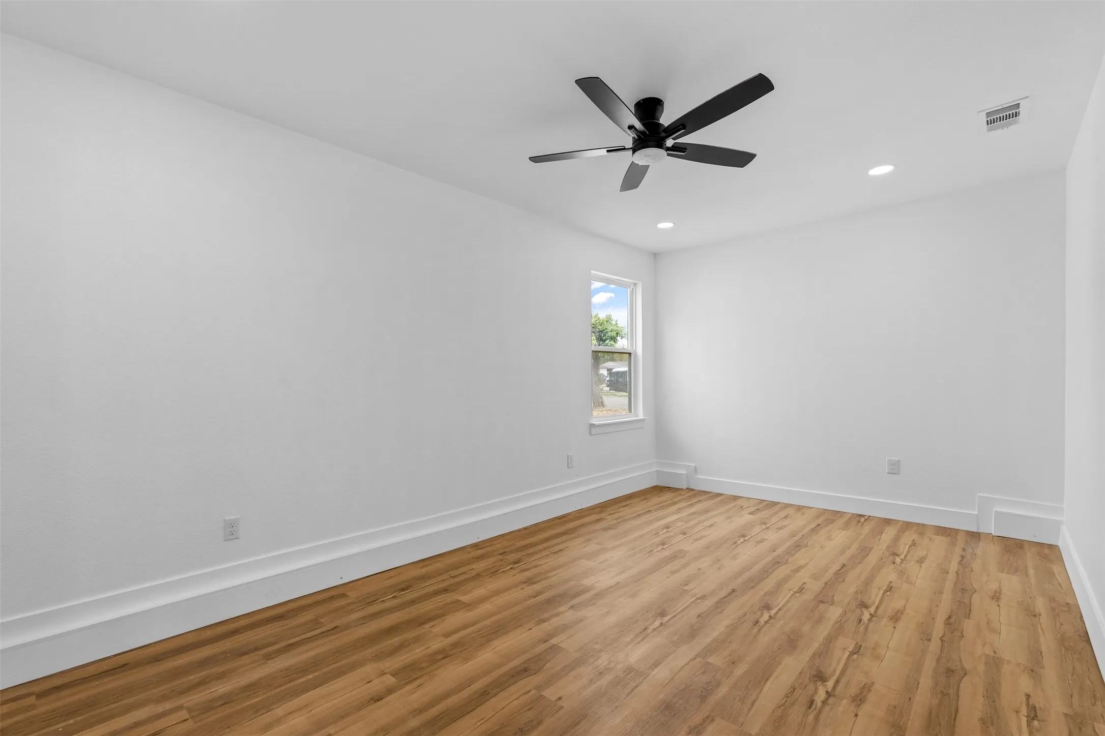 Wood-finish flooring, white walls, and a single window