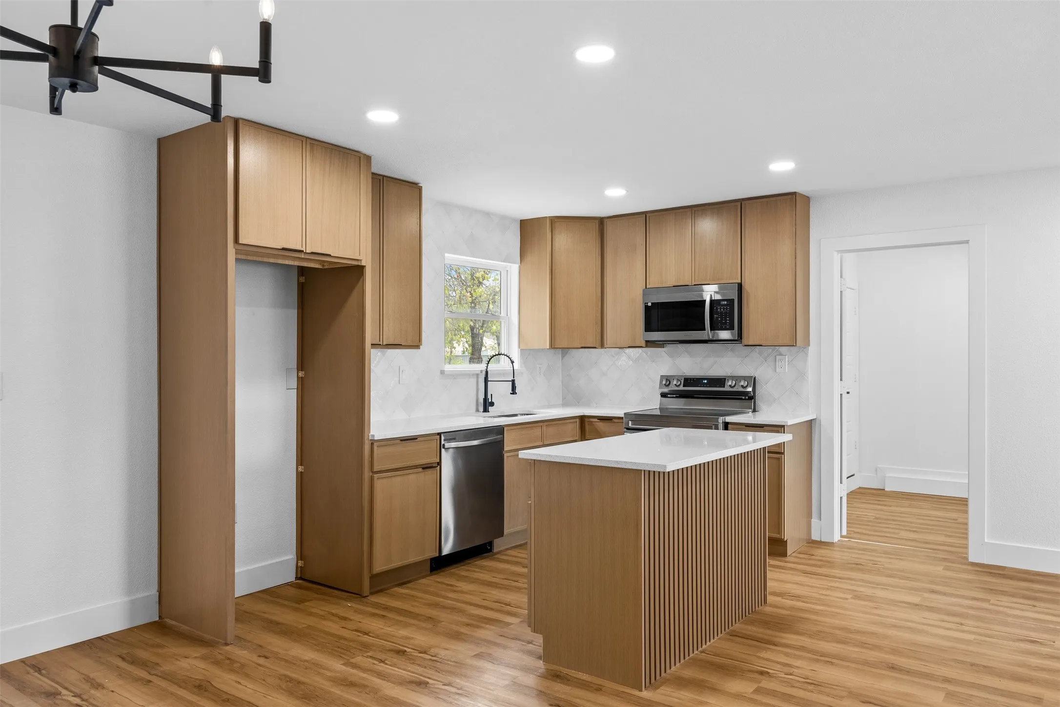 Modern kitchen featuring wood-finish cabinetry, stainless steel appliances, a center island with countertop, recessed lighting, and wood-finish flooring