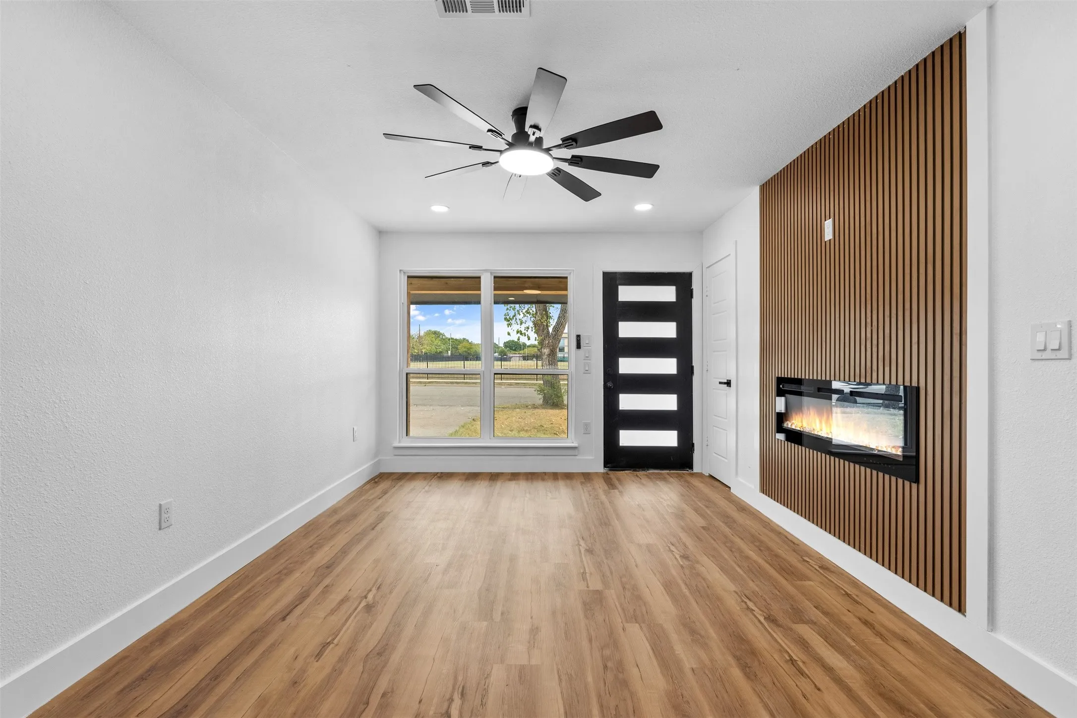 Wood-finish flooring, white walls, and a modern ceiling fan with lighting