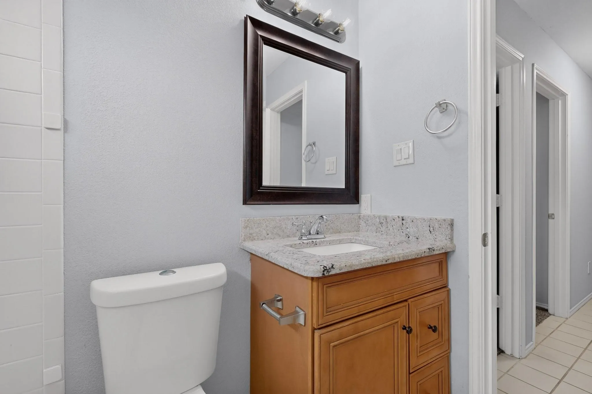 Vanity with light wood-finish cabinetry, integrated sink, and stone-finish countertop