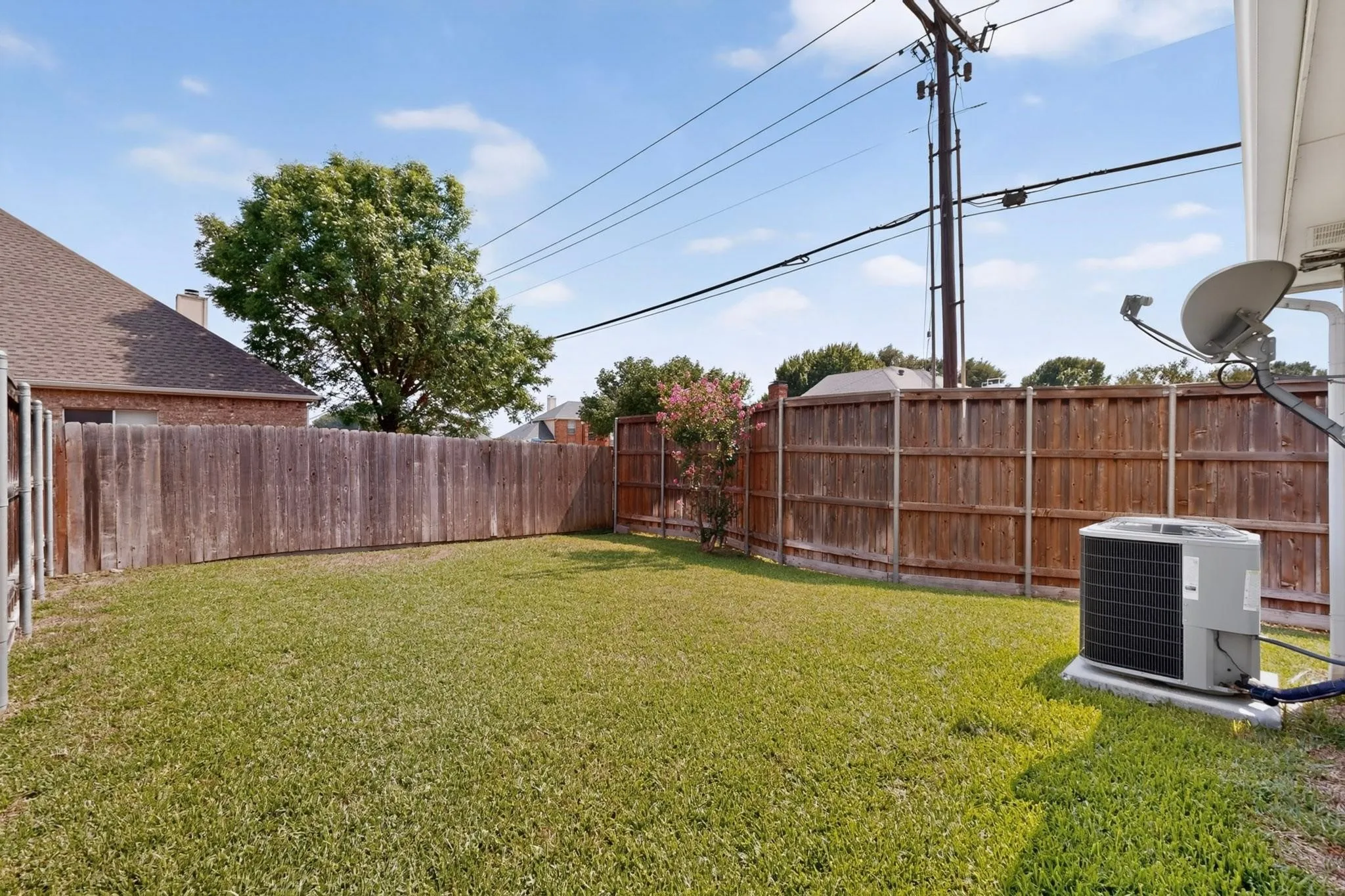 Grassed backyard featuring a wood fence perimeter and mature trees