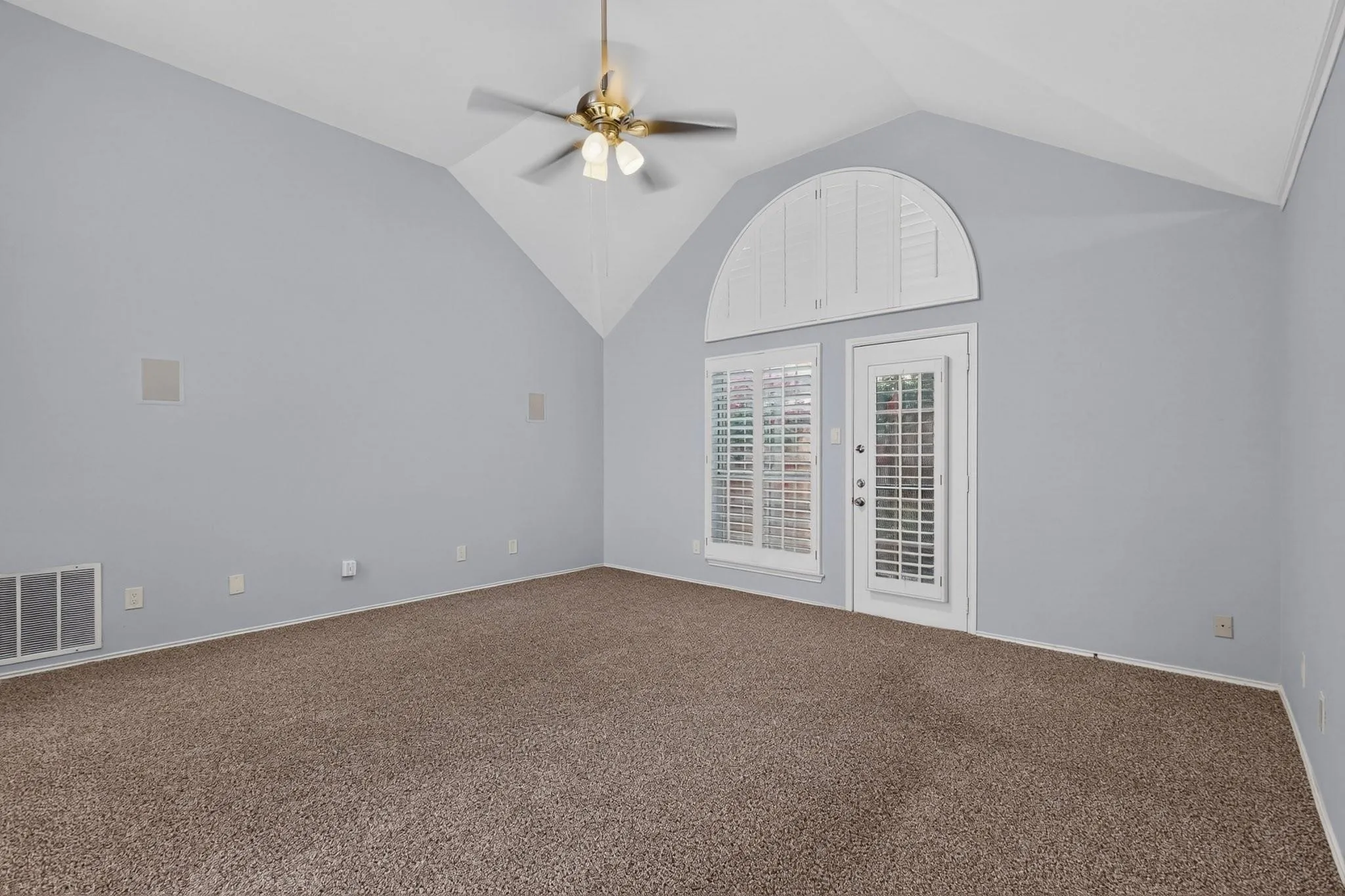 Vaulted ceiling with a brass-finish ceiling fan and light fixture