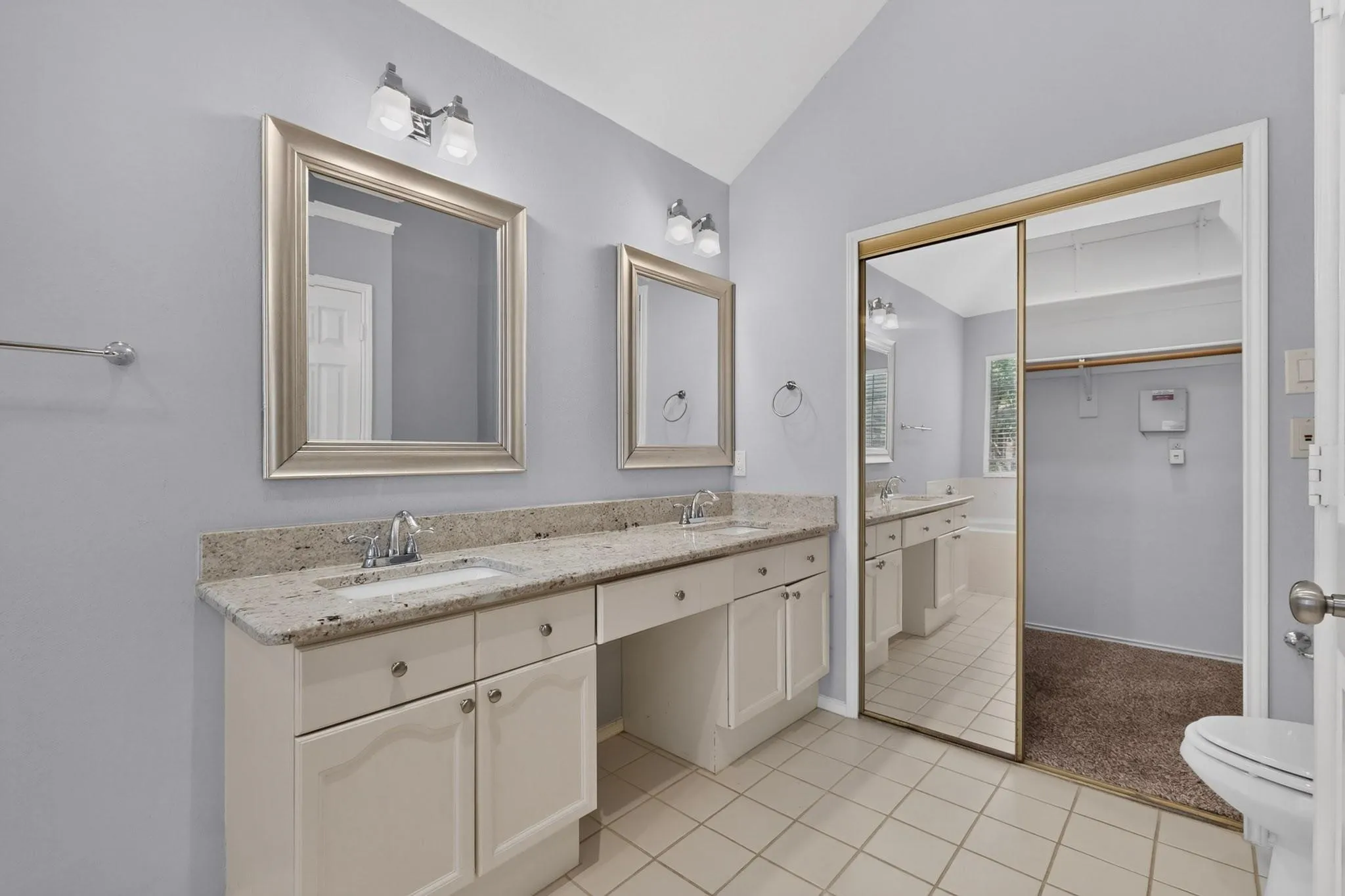 Dual vanity with light-toned countertop, framed mirrors, and chrome fixtures