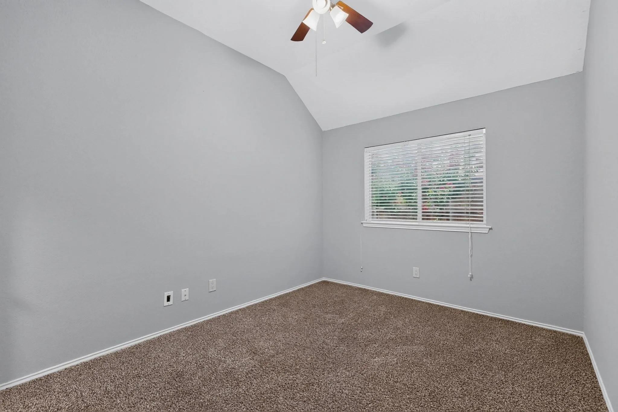Vaulted ceiling with ceiling fan, window with blinds, and neutral carpet flooring