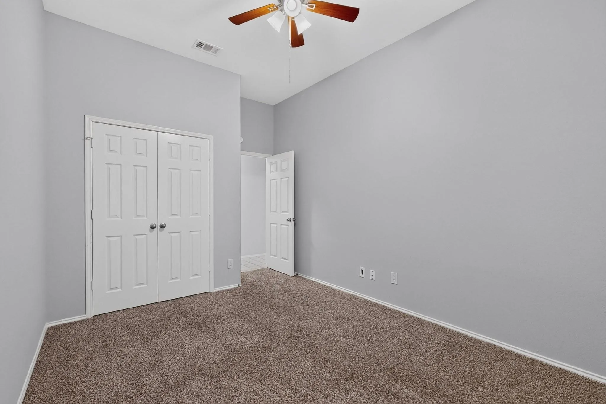 Neutral gray wall finish, brown carpet, bi-fold closet doors, paddle ceiling fan, and white trim