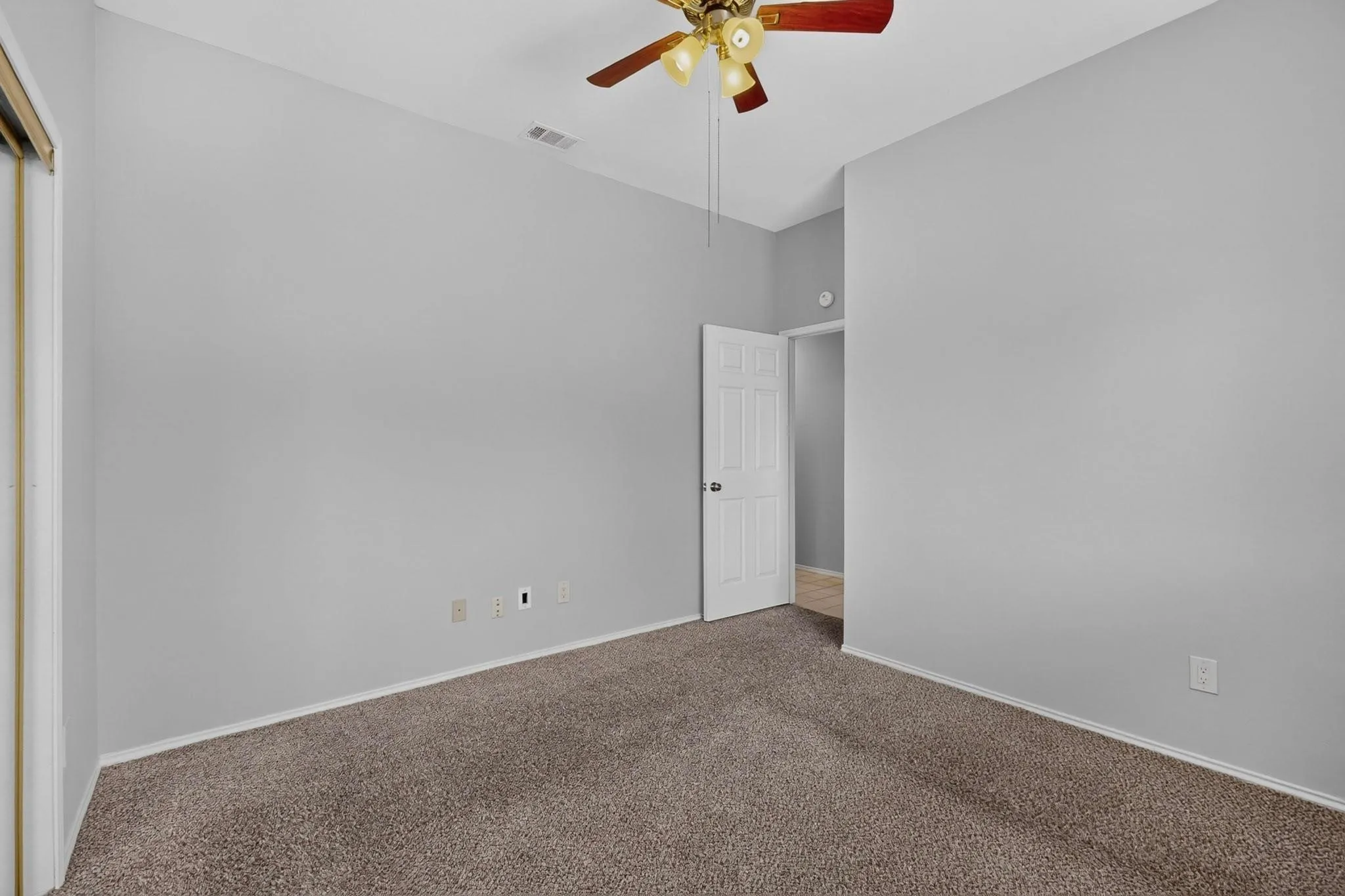 Carpeted flooring with painted walls, a ceiling fan, and a white interior door