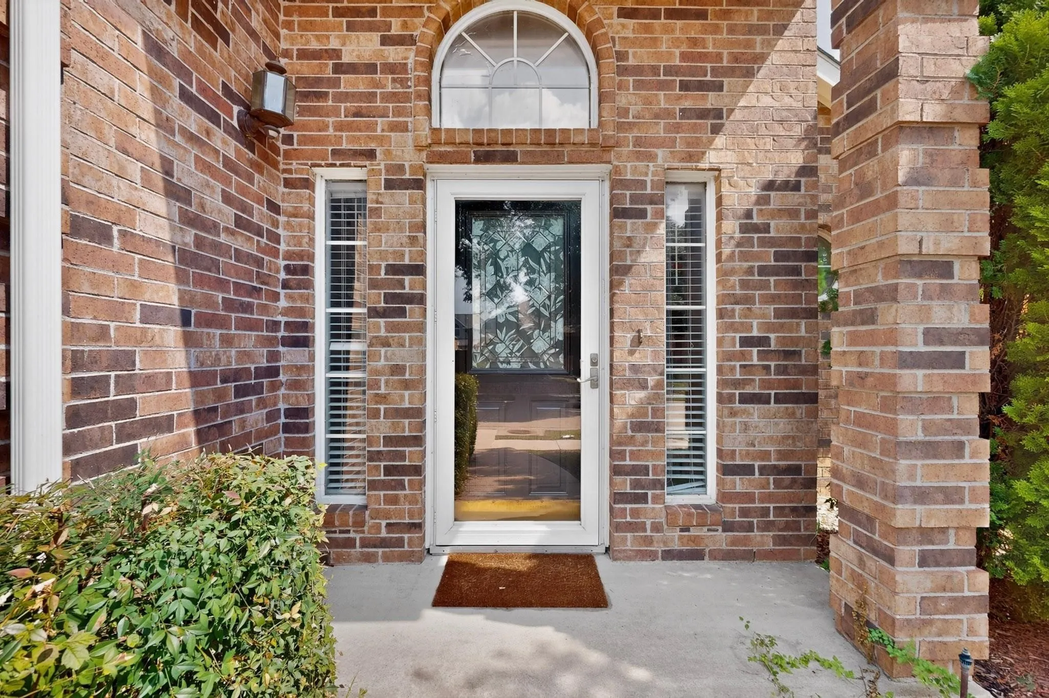 Brick exterior with a prominent arched window above the entry door, flanked by two vertical windows