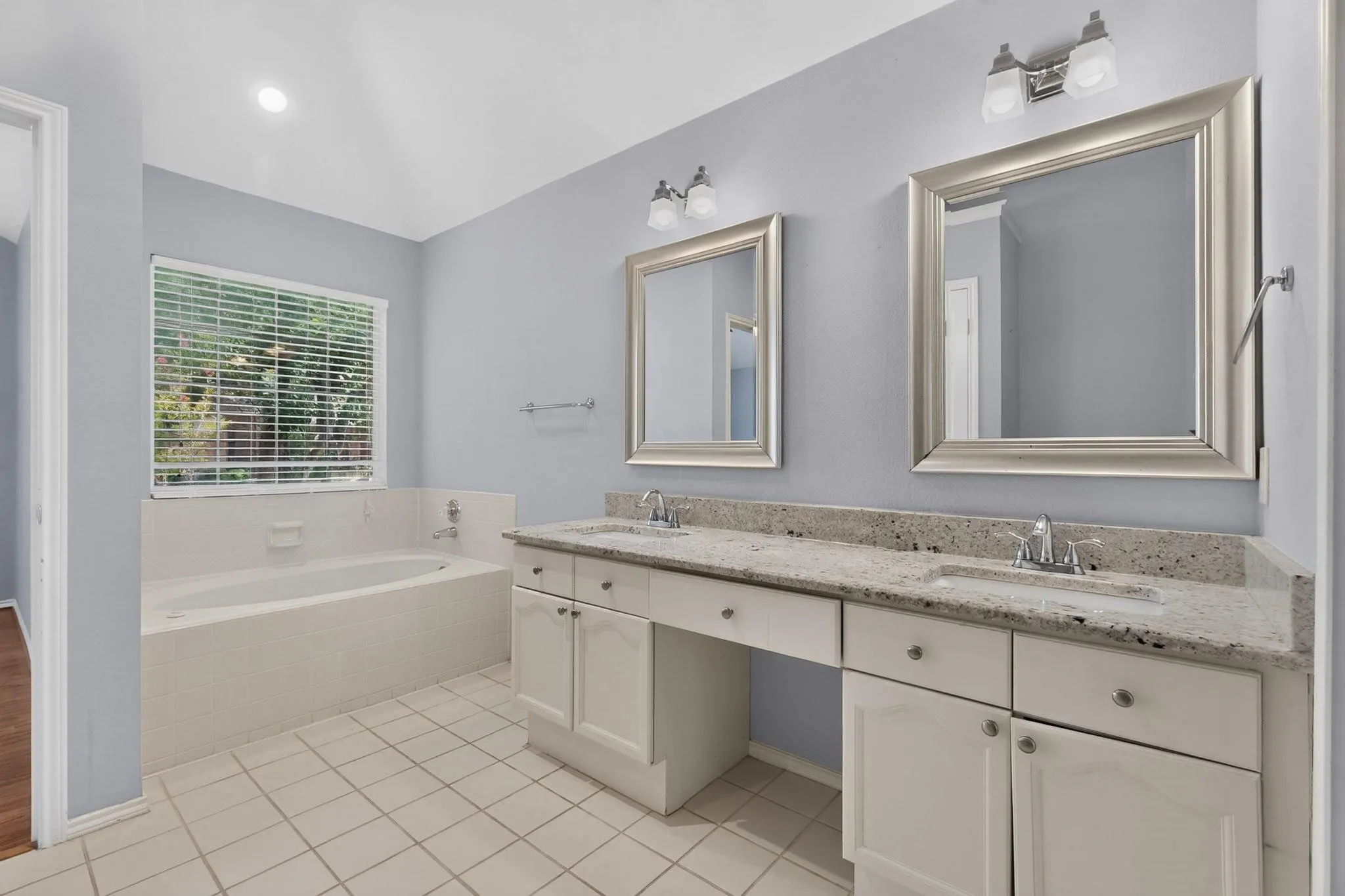 Dual vanity with stone-finish countertop, framed mirrors, undermount sinks, and built-in cabinetry