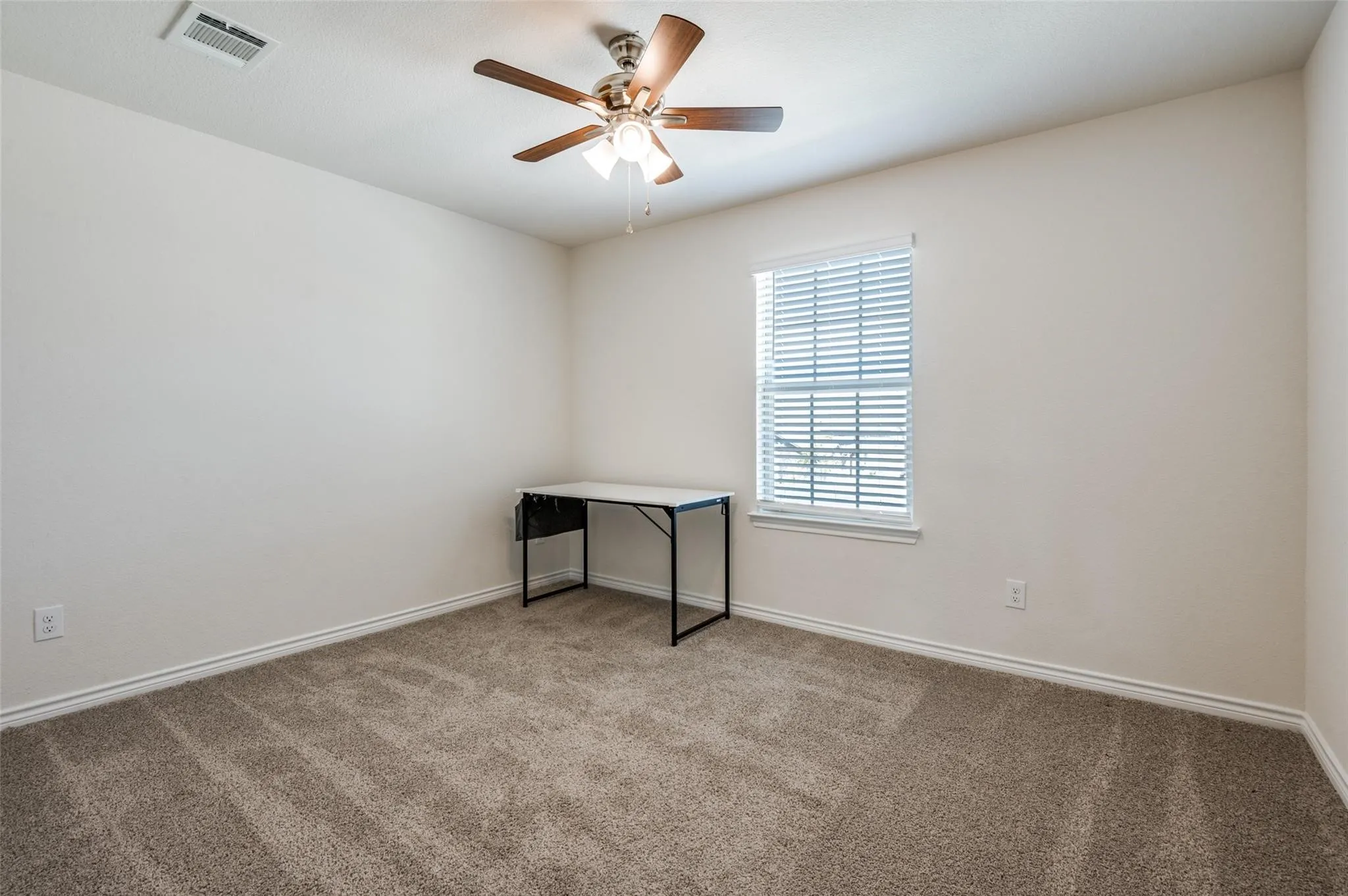 Carpeted room featuring a ceiling fan with integrated lighting and a window with blinds