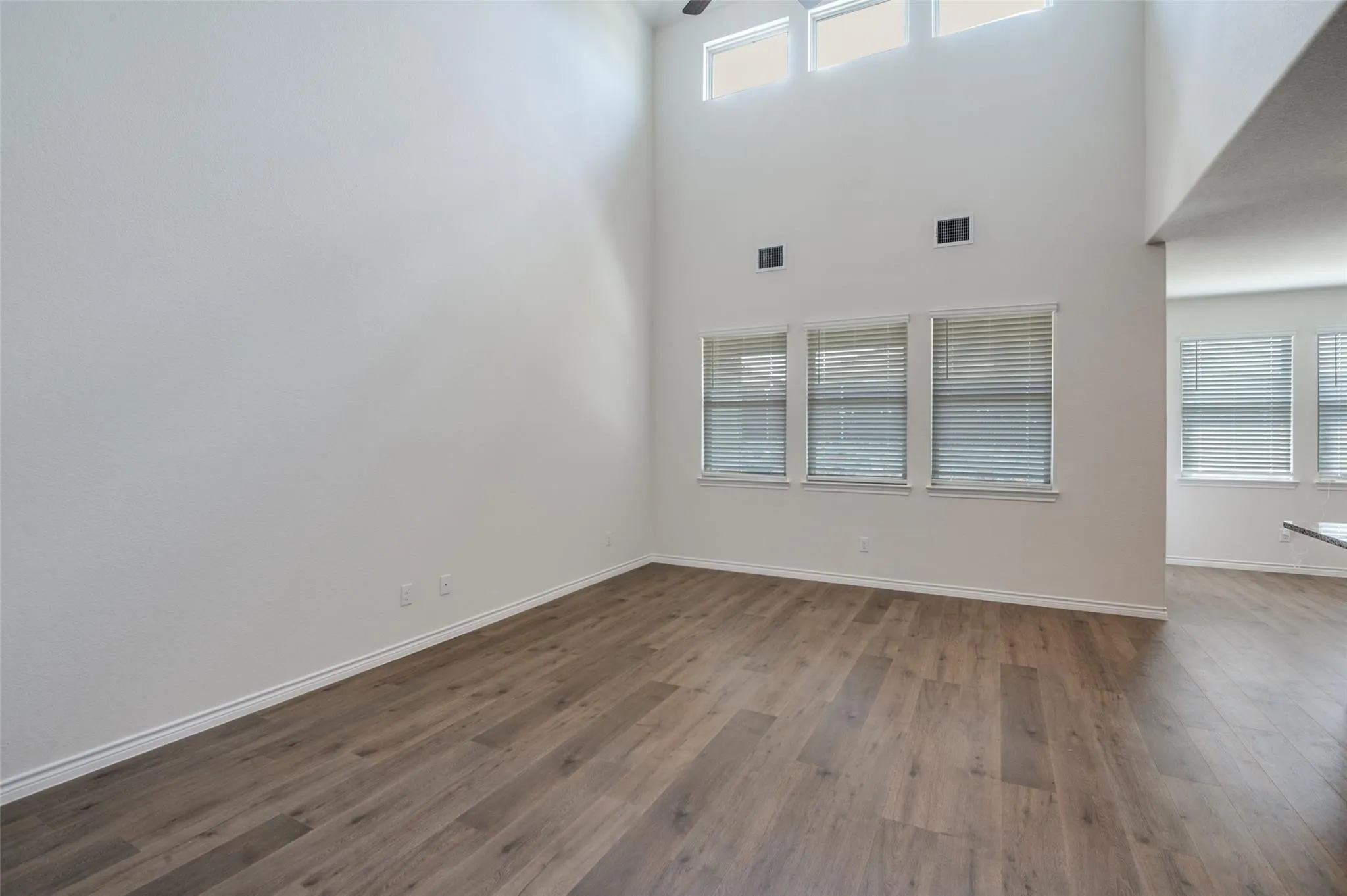 Vaulted ceilings, wood-finish flooring, and multiple windows with blinds