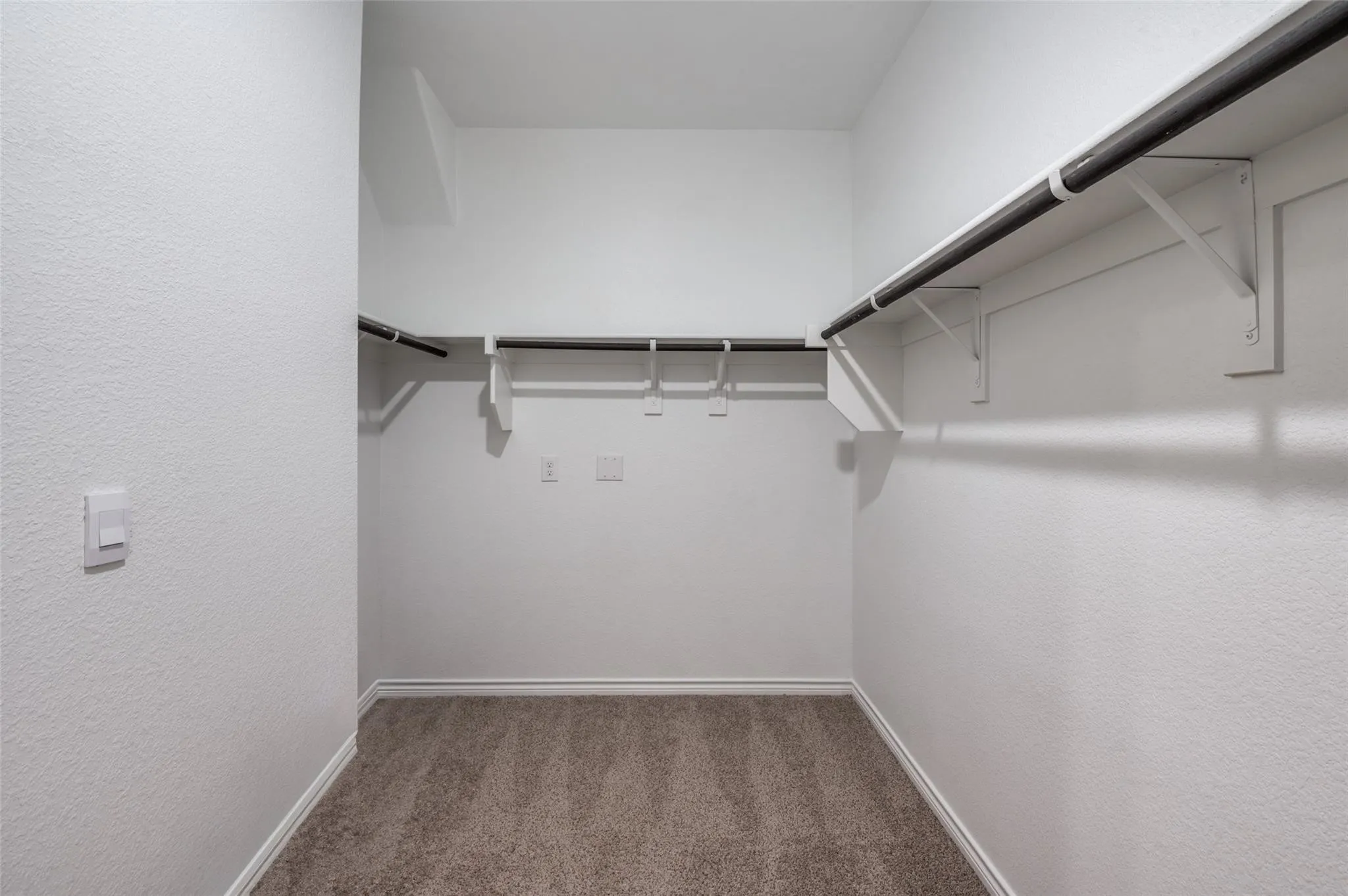 Walk-in closet with carpet flooring, multiple hanging rods, and shelving