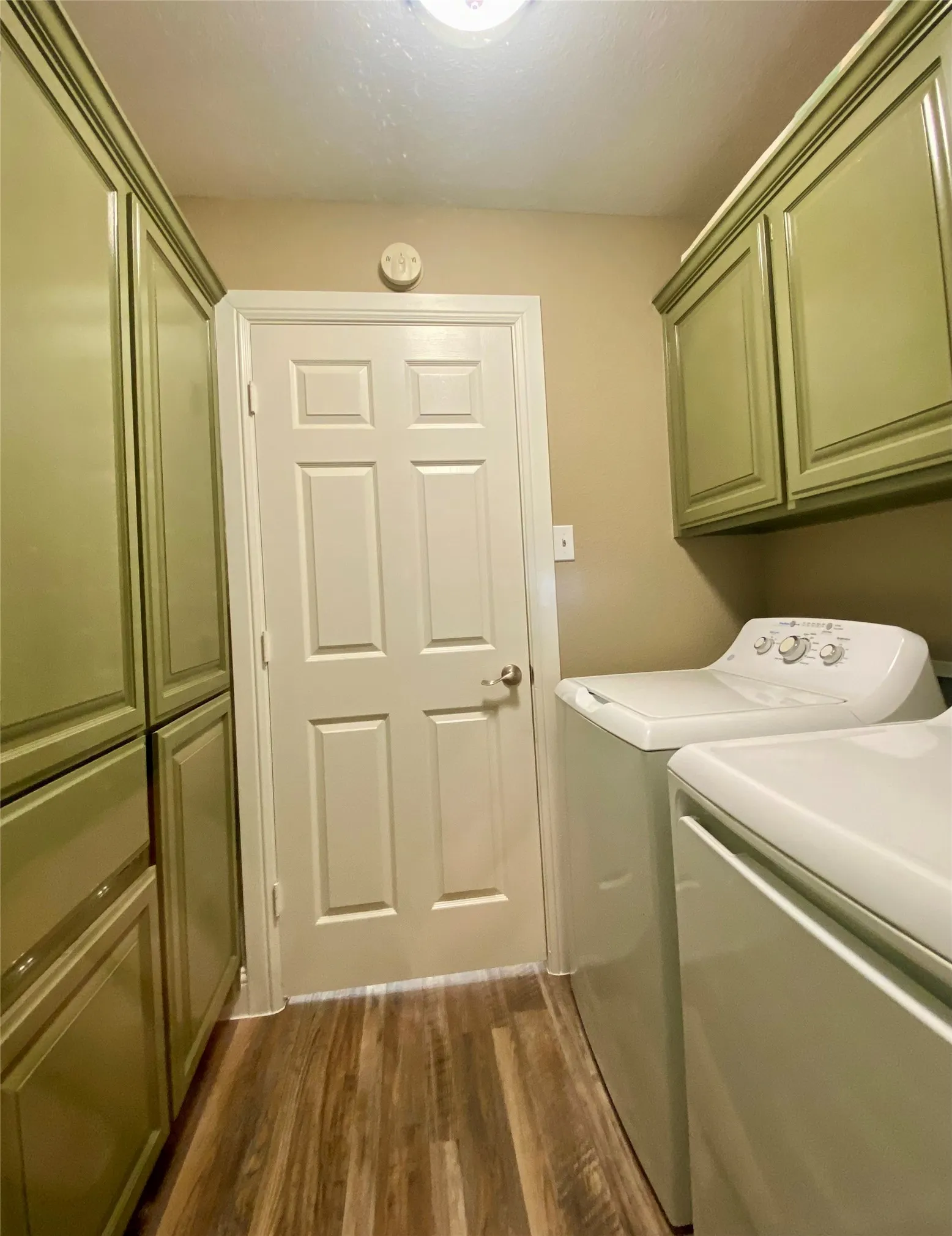 Laundry going into kitchen Wood-finish flooring with a neutral color palette