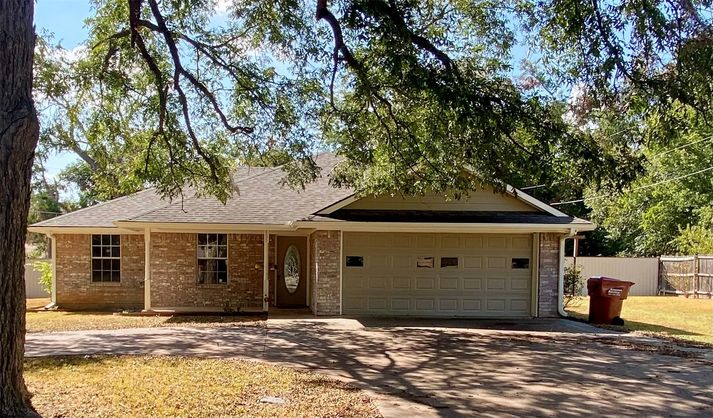 Brick exterior with stone accents, covered front porch, attached two-car garage, and a fenced backyard