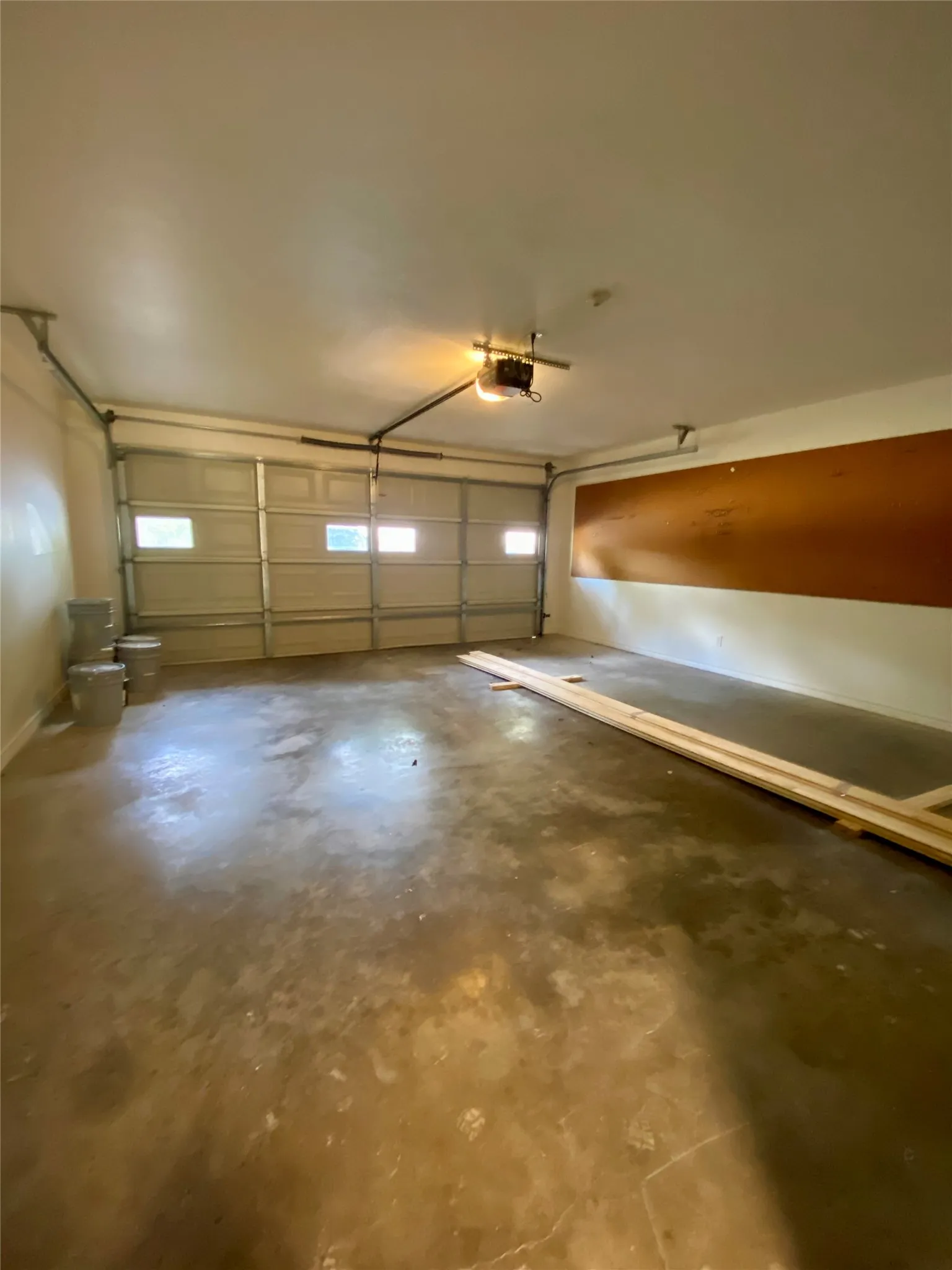 Garage space featuring a roll-up door with integrated windows, an automatic opener, and concrete flooring