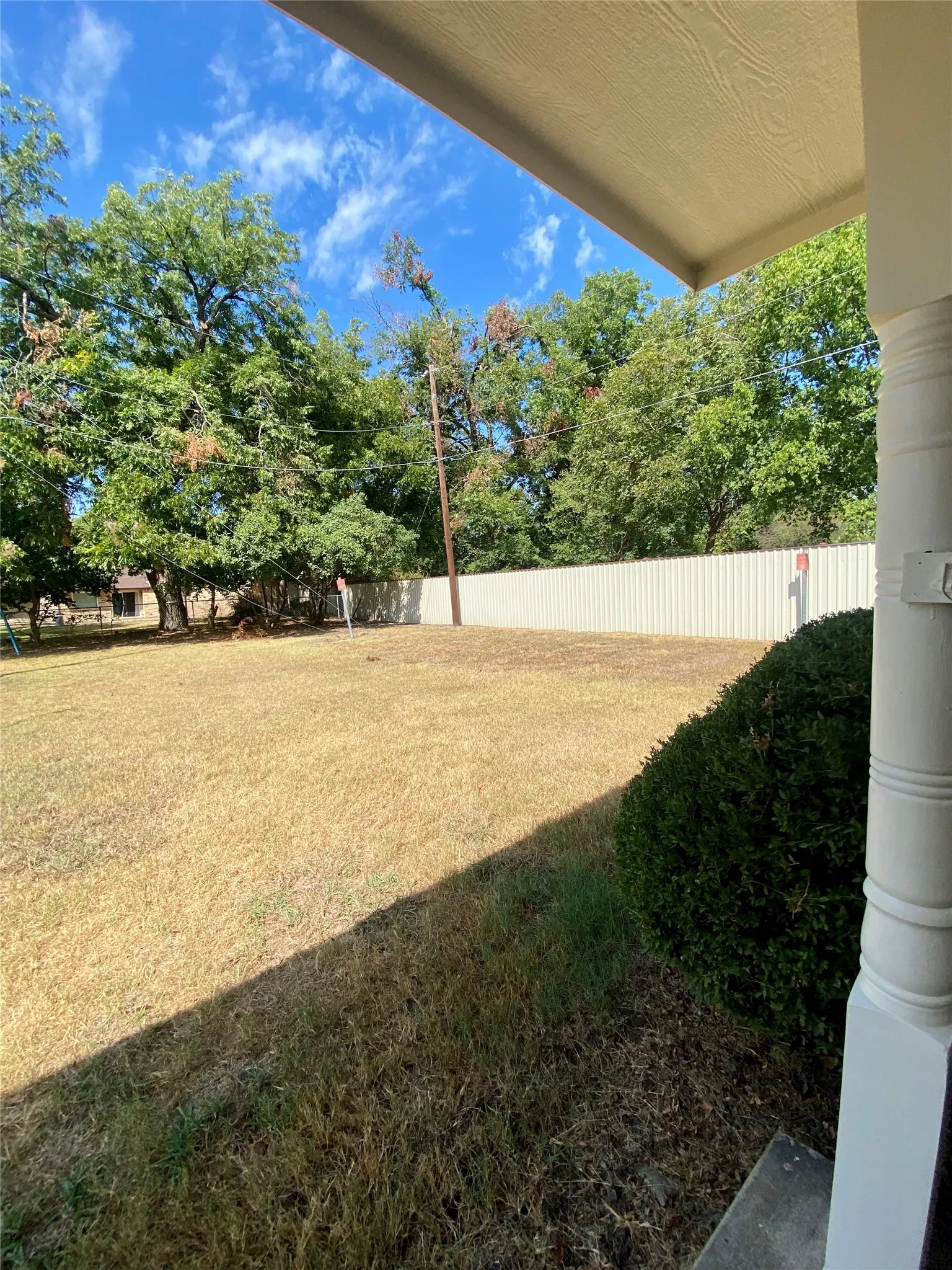 Backporch looking NW Expansive exterior space featuring a large lawn area, mature trees, and privacy fencing