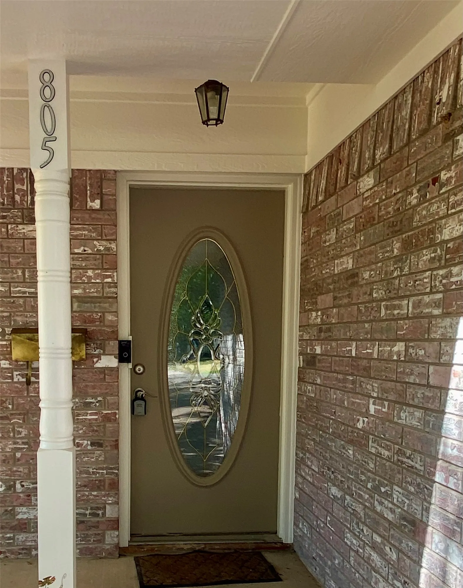 Front entry featuring a decorative glass door, brick facade, and a classic outdoor light fixture