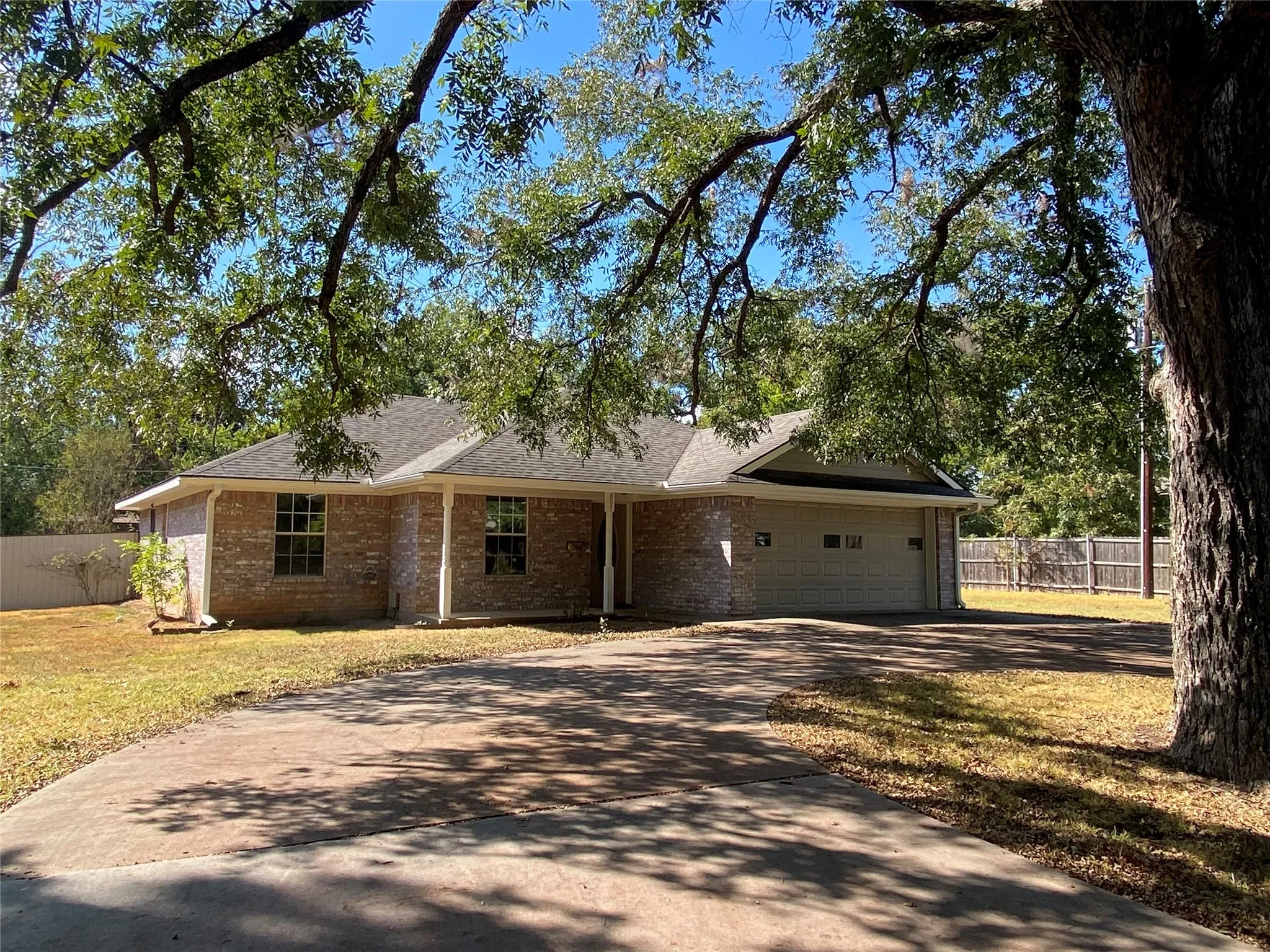 East elevation brick exterior, attached garage, covered front entry, and fenced backyard