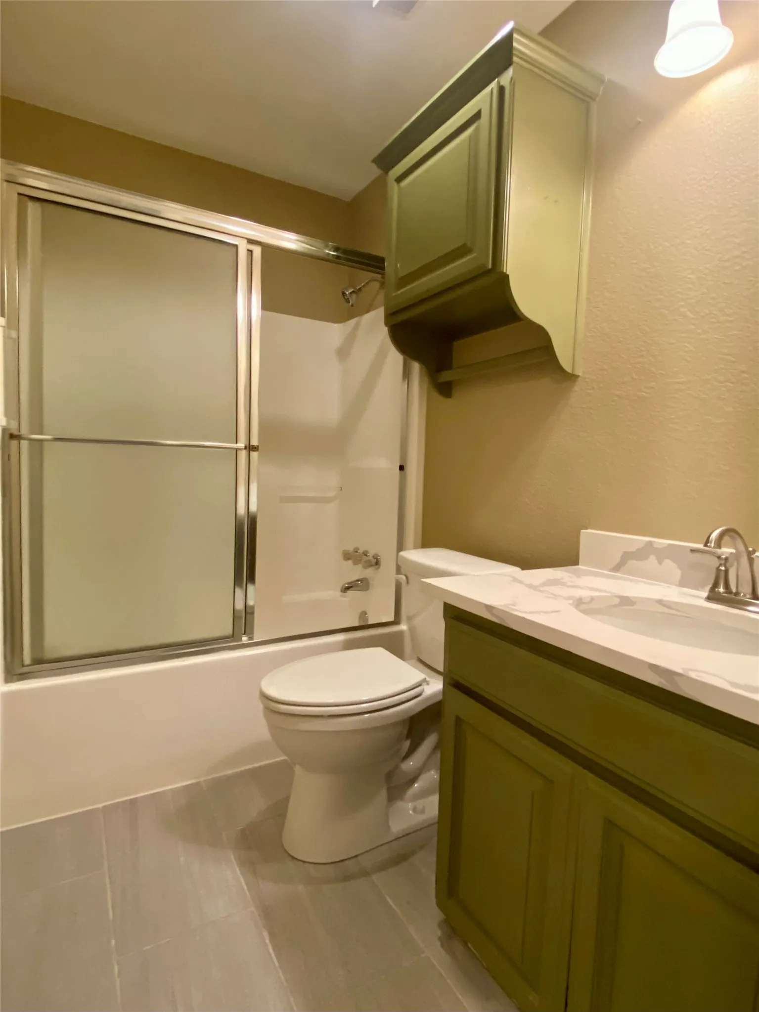 Guest Bathroom featuring a shower/tub combination with sliding glass doors, a vanity with a white countertop and integrated sink, a toilet, and wall-mounted cabinetry