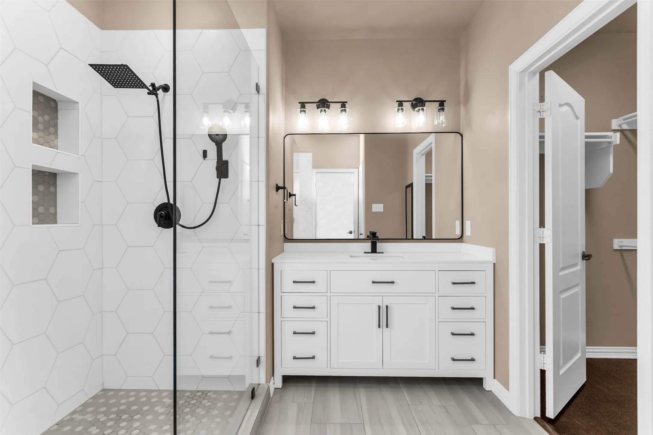 Walk-in shower with hexagonal tile, dual shower heads, and built-in niches