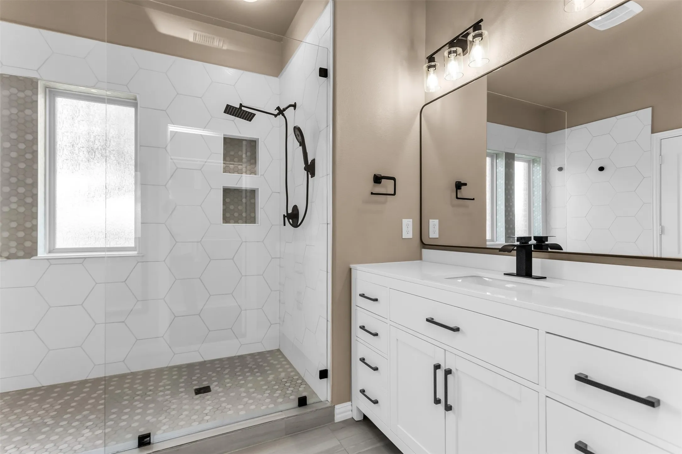Frameless glass shower enclosure with hex tile walls and mosaic floor