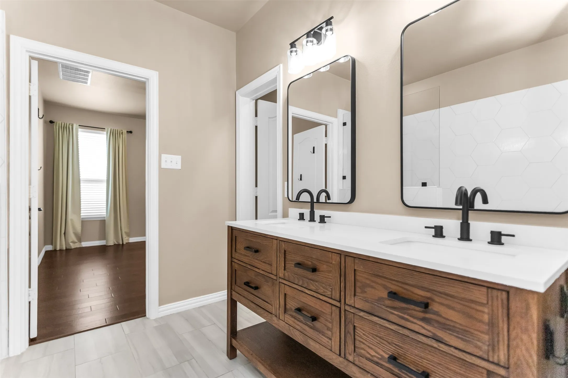 Dual vanity with white countertops, matte black fixtures, and wood-finish cabinetry