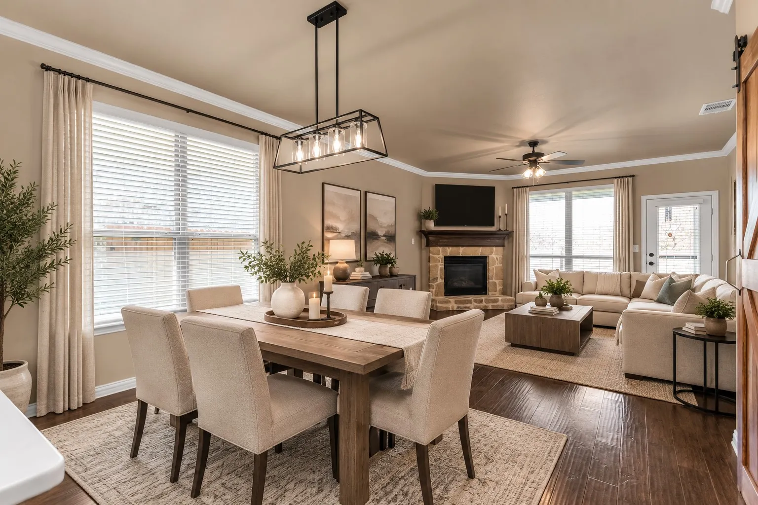 Open-concept living space featuring wood-finish flooring, a stone-surround fireplace with a wood mantle, and an overhead ceiling fan