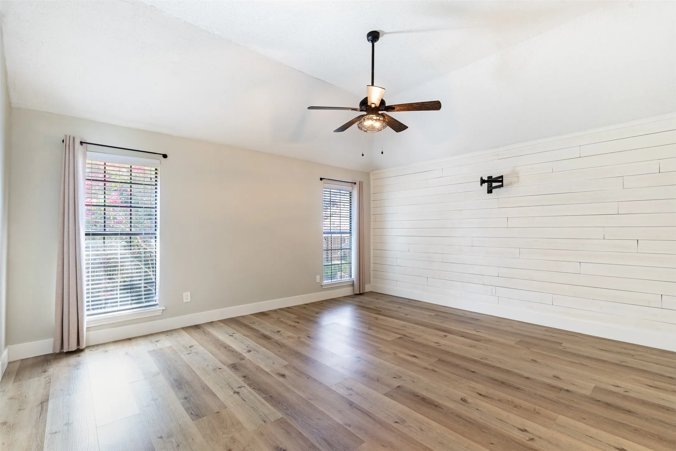 Primary suite with shiplap accent wall and vaulted ceiling.