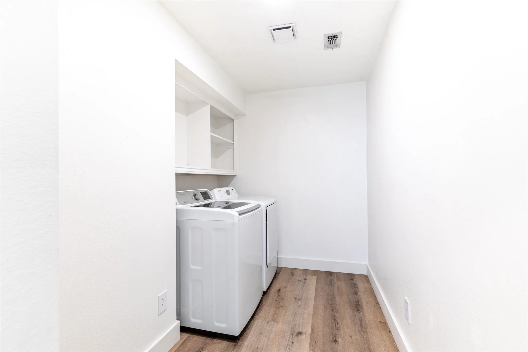 Large laundry room with shelving and room for additional fridge.
